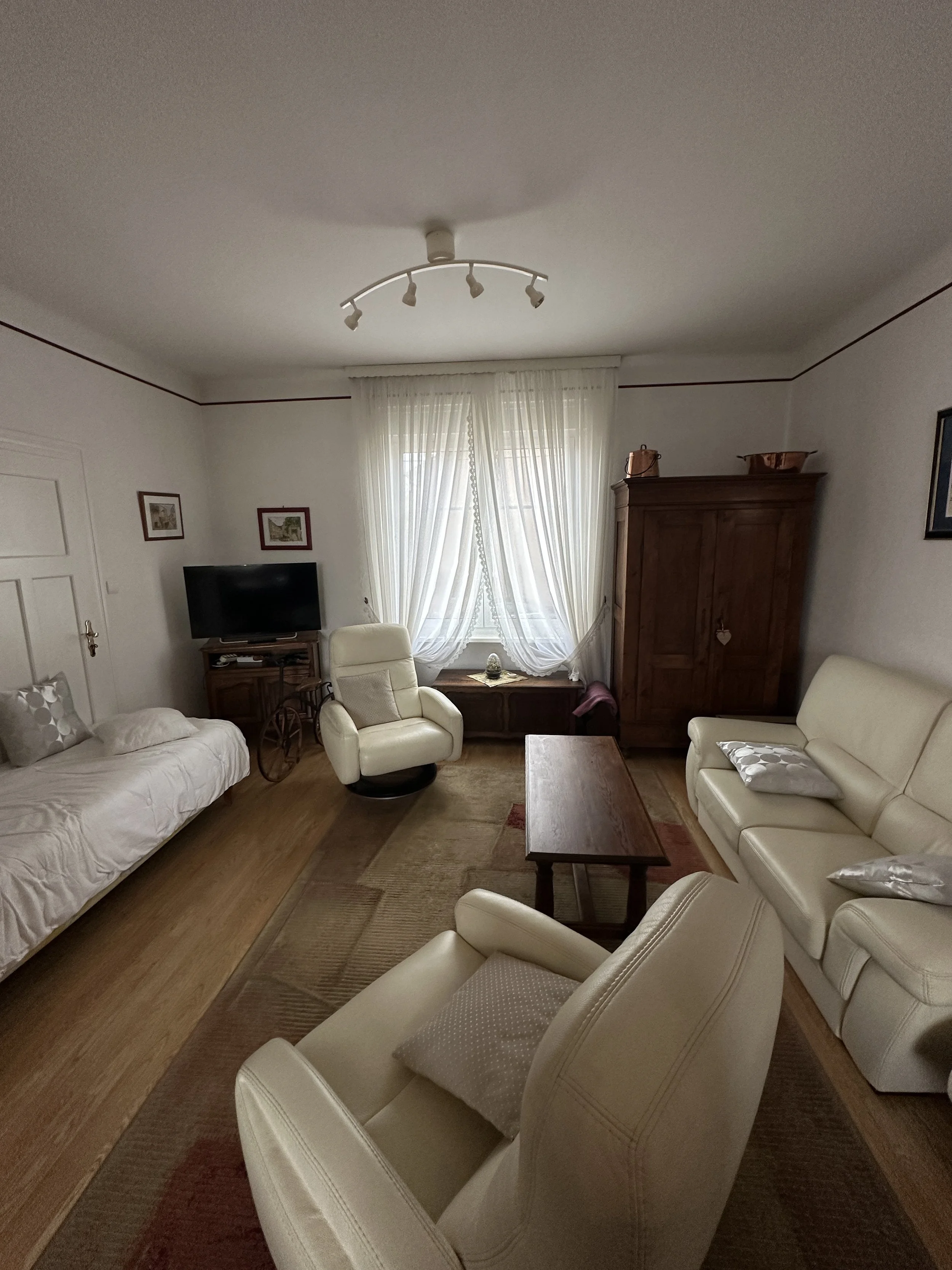 État avant travaux – salon maison de maître avec canapés cuir crème, mobilier rustique hérité, parquet pin et spots plafond – avant transformation par Anthony Mambré Design, architecte d'intérieur