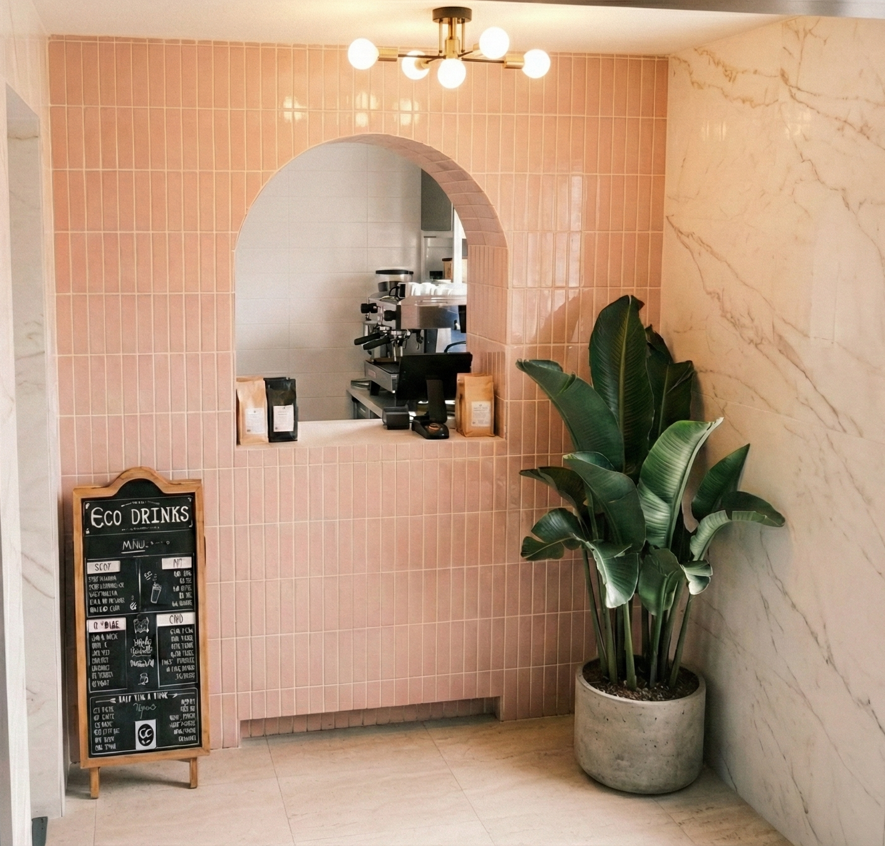 Zone d'accueil pâtisserie rénovée avec carrelage rose poudré, arche guichet encadrée, lustre laiton sphères et mur effet marbre – aménagement commerce et ERP à Lyon, Anthony Mambré Design architecte d'intérieur