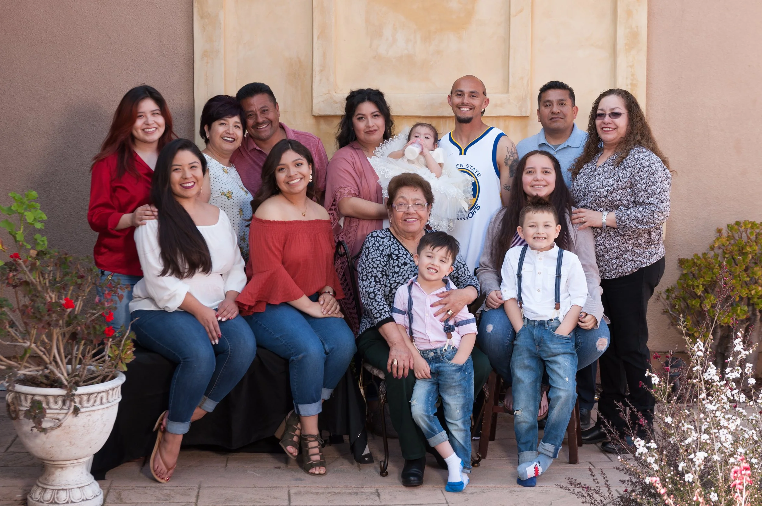 A large multigenerational family gathered together for a group photo outdoors, with some children and adults smiling.