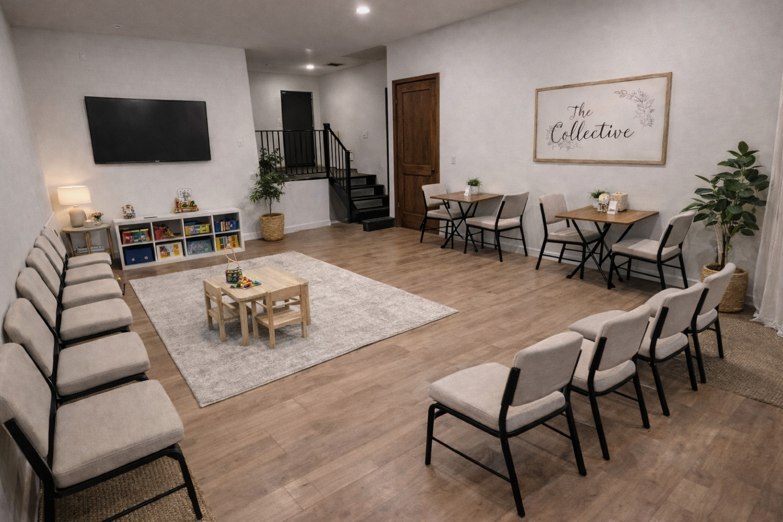 A spacious indoor room with multiple rows of chairs arranged for an event, a large TV on the wall, a small bookcase with toys and books, a table with toys, a cozy rug, and decorative plants. The walls are decorated with a sign that reads 'The Collective'.