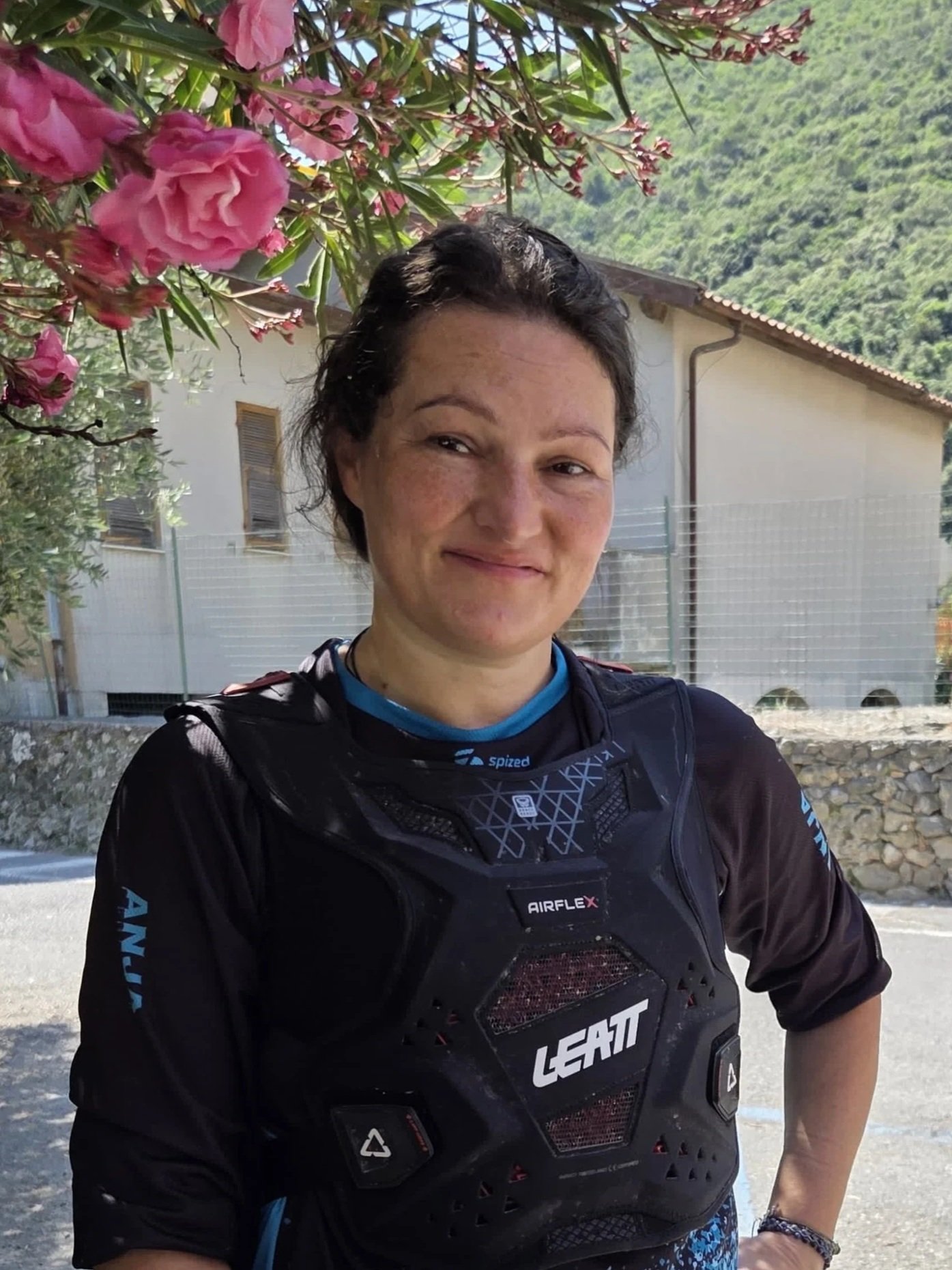 Anja Steht in der Mittagshitze unter schönen rosanen Blumen in Finale Ligure