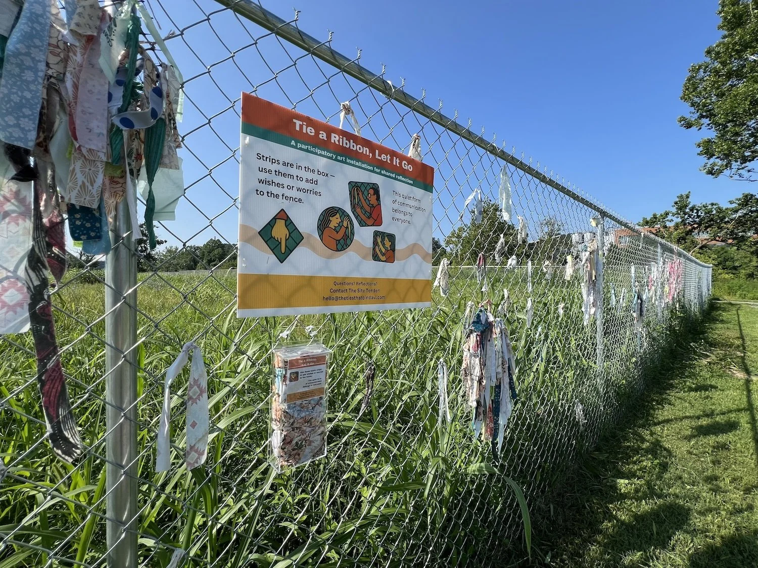 Reattached the box to the fence and restocked it with fabric strips for new participants.