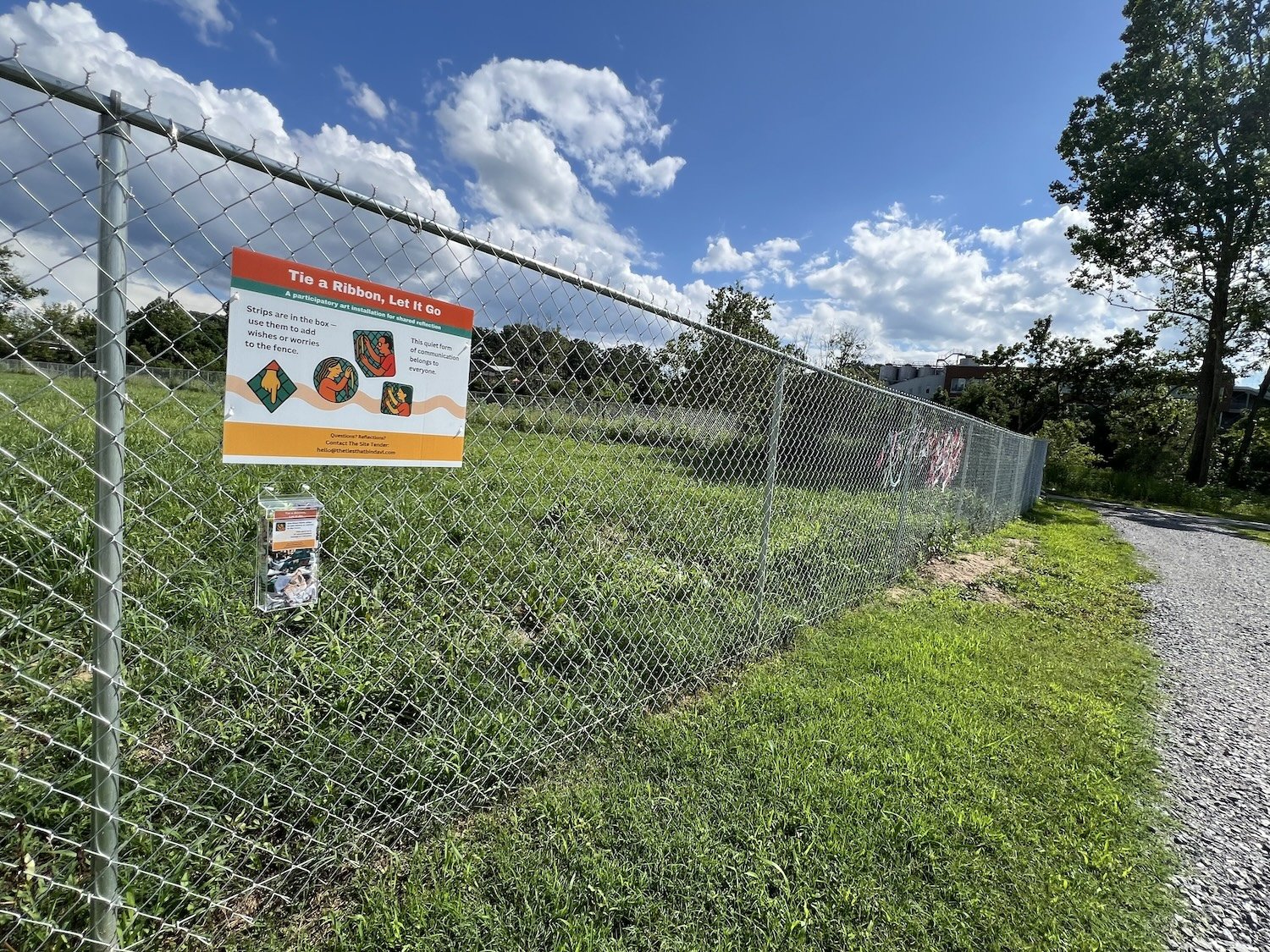 Early phase of The Ties That Bind Asheville installation showing project sign, fabric strip box, and initial fabric strips in Asheville, North Carolina.