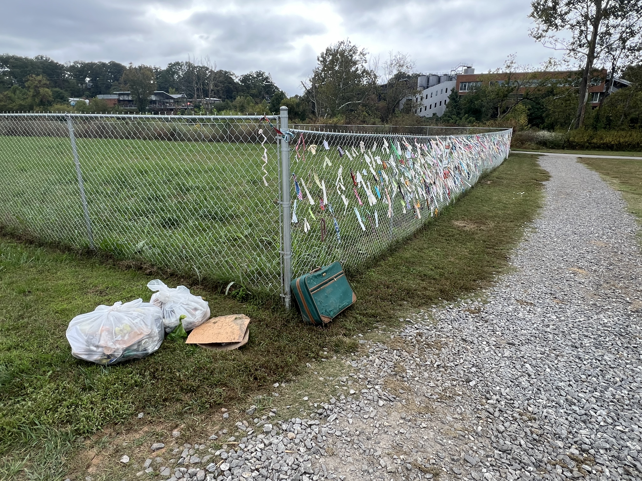 Organized trash containers appear beside  fence while site awaits replacement trash cans.