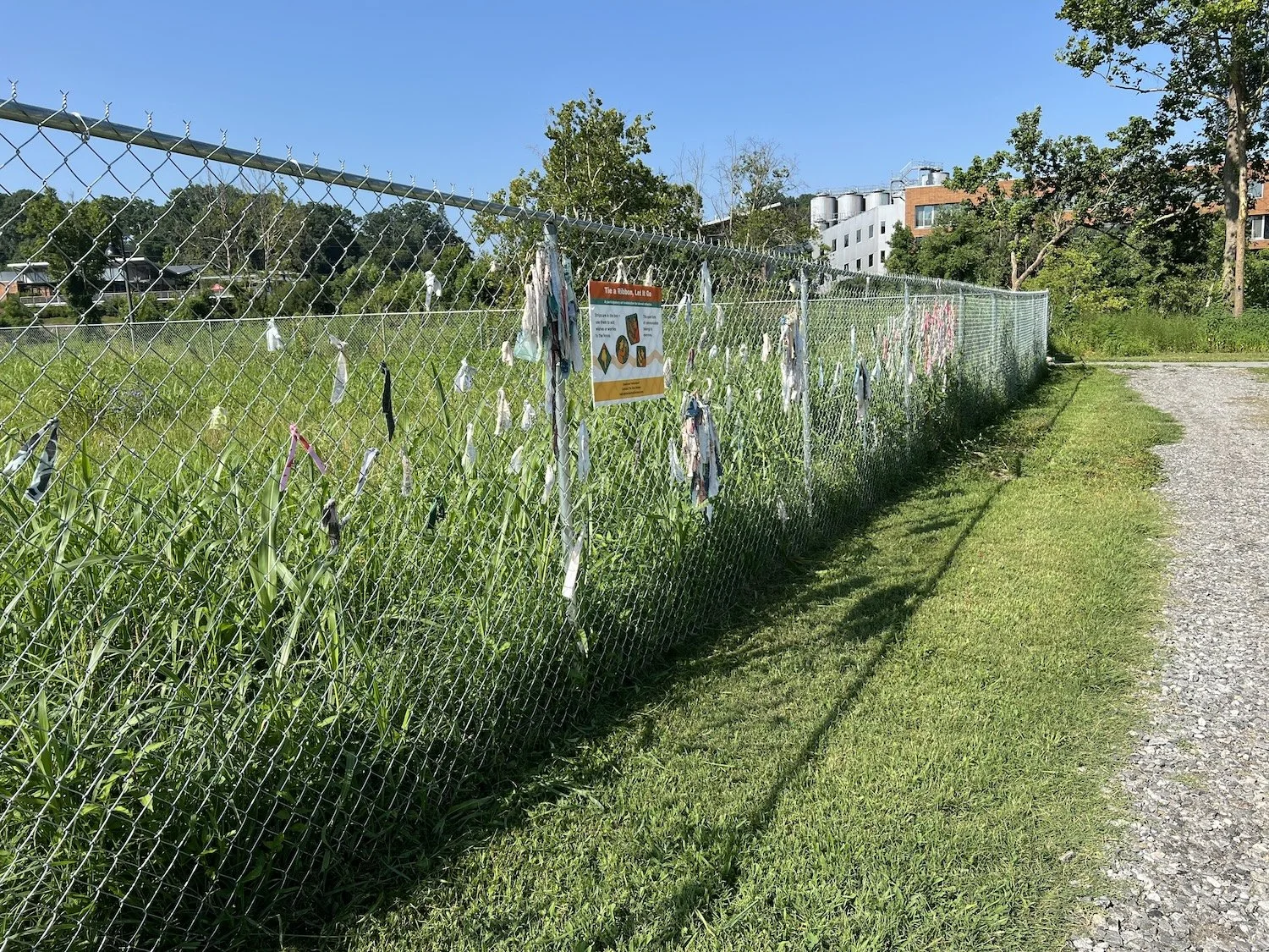 Textile accumulation continues expanding toward the riverside portion of the fence.