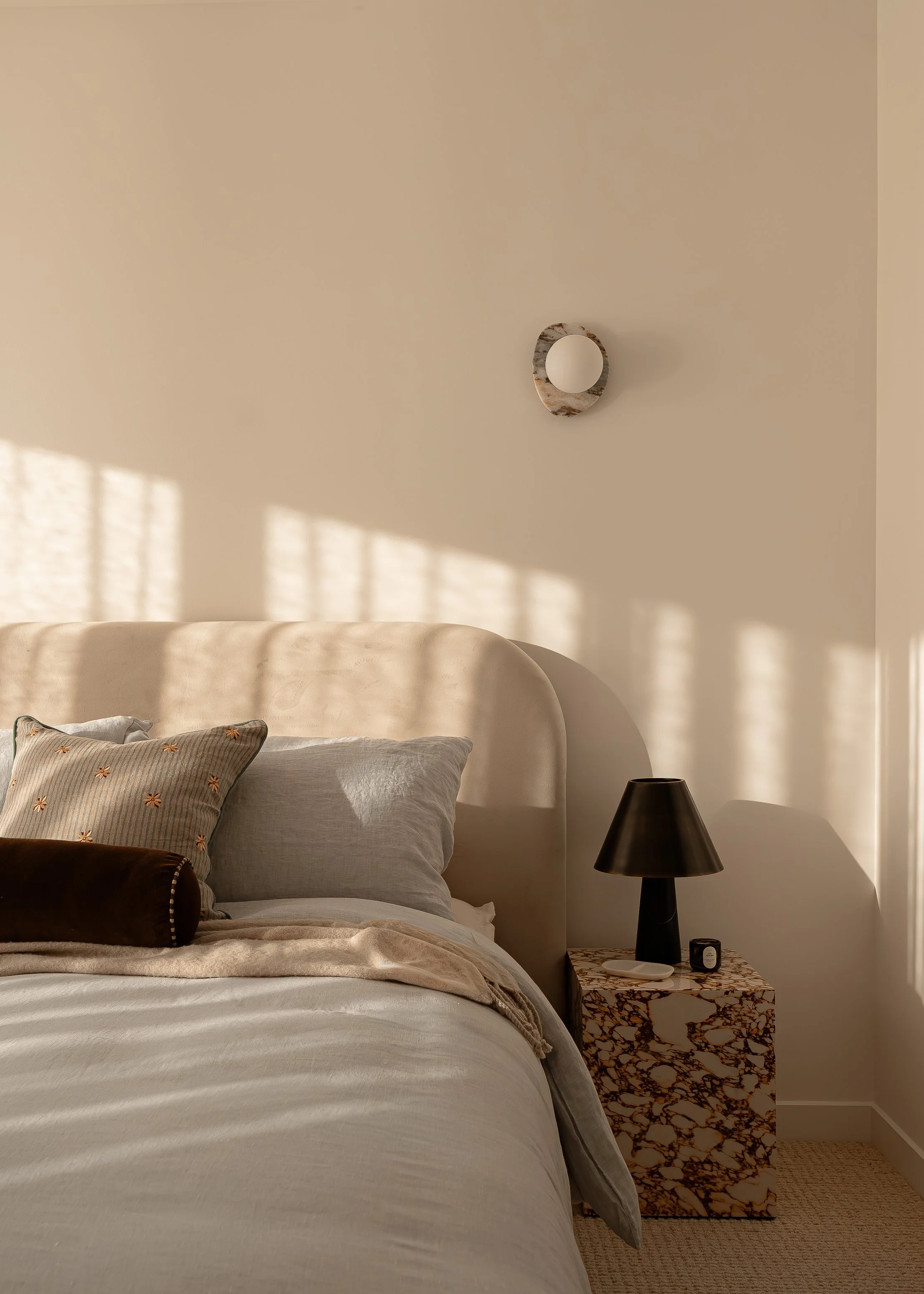 beautifully styled blue bed and marble side table with lovely afternoon dappled light,