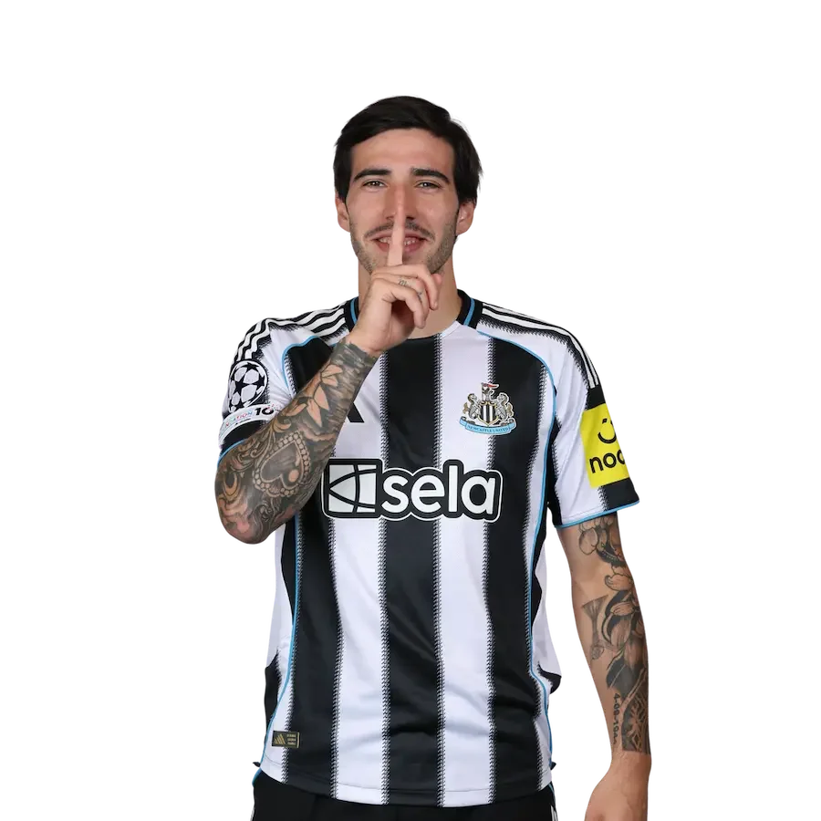 A man wearing a Newcastle United football jersey with tattoos on his arms, making a shushing gesture with his finger over his lips.
