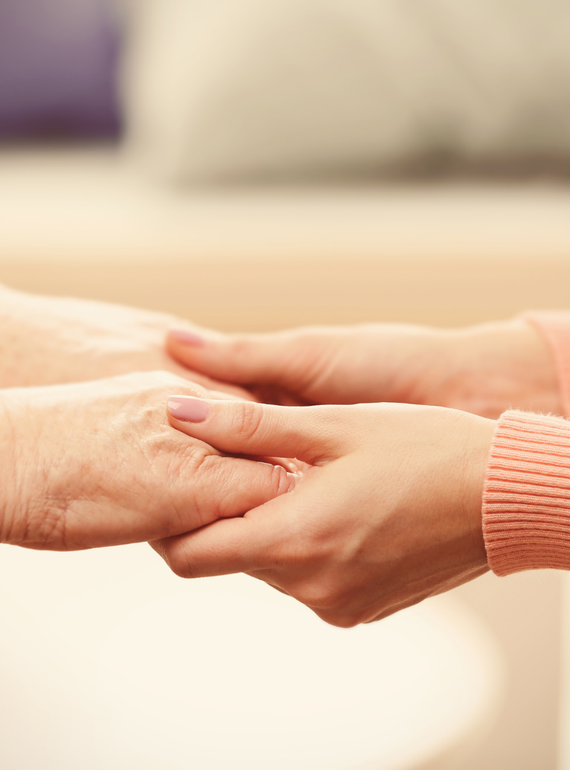 A close-up of a younger person holding hands with an older person, showing care and connection.