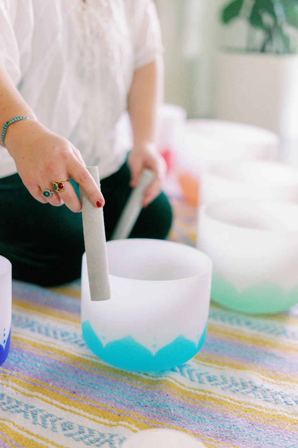 McKinley Merchant, LCSW placing a white mallet into a turquoise singing bowl during a sound bath