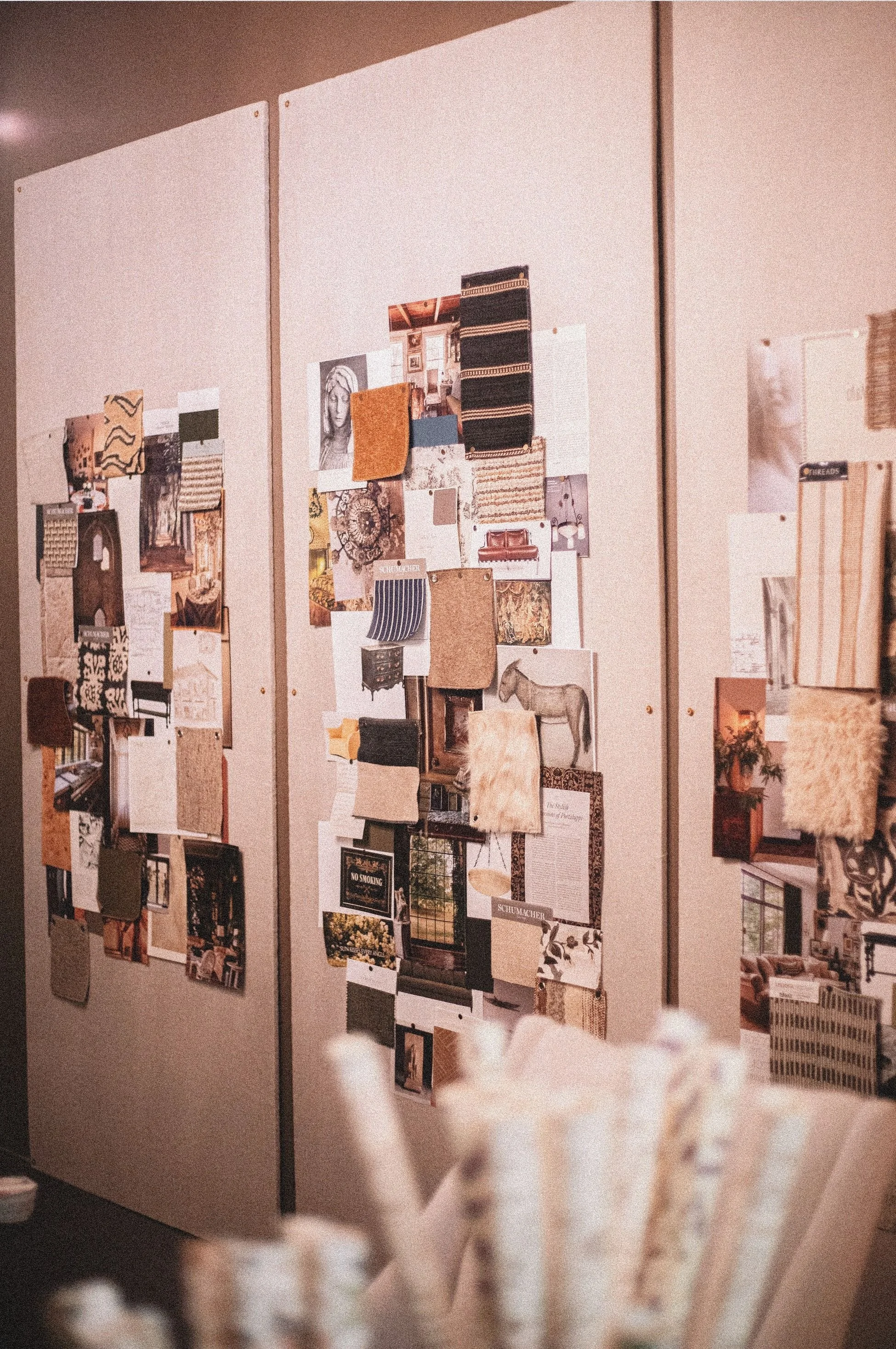 Close-up of a bulletin board filled with various magazine clippings, photographs, and paper swatches in an interior setting.