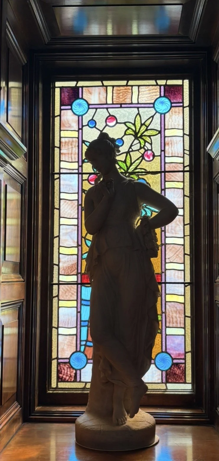 classical marble statue of a woman in front of stained glass