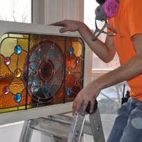 worker installing stained glass into a window