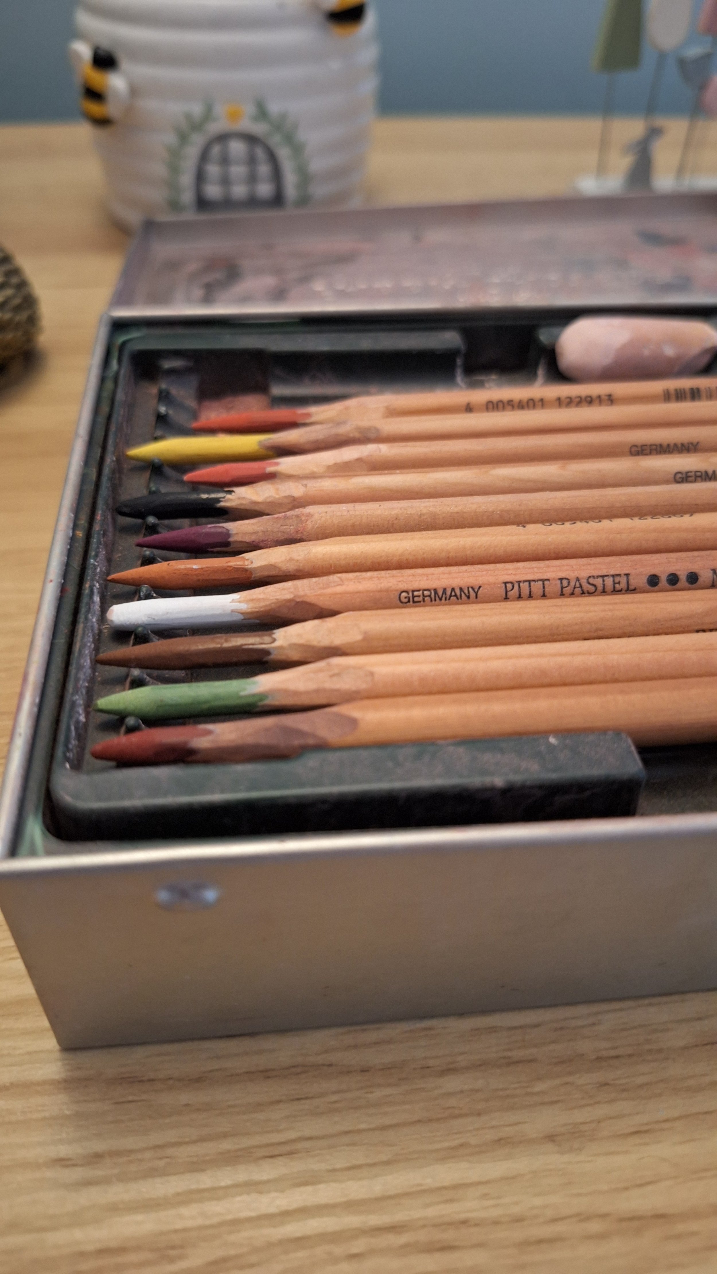 Set of colored pencils in a box on a wooden table.