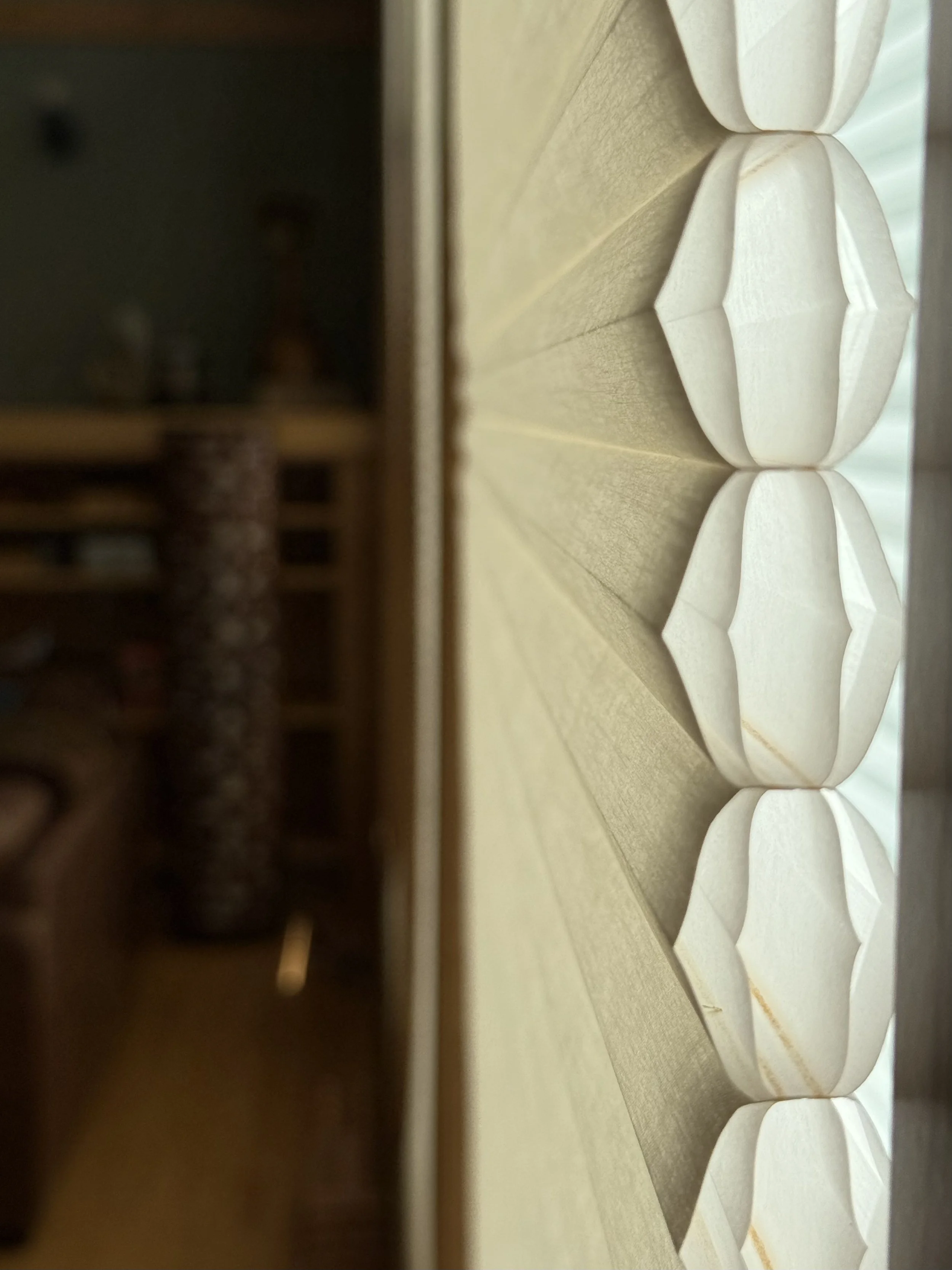 Close-up view of blinds fabric with white, petal-shaped lamps, aligned in a row on a wooden surface.