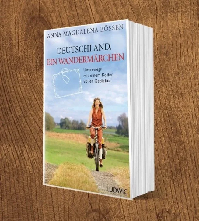 Buchcover mit Titel 'Deutschland. Ein Wandermärchen' von Anna Magdalena Bösen, zeigt eine junge Frau auf einem Fahrrad in einer ländlichen Landschaft.