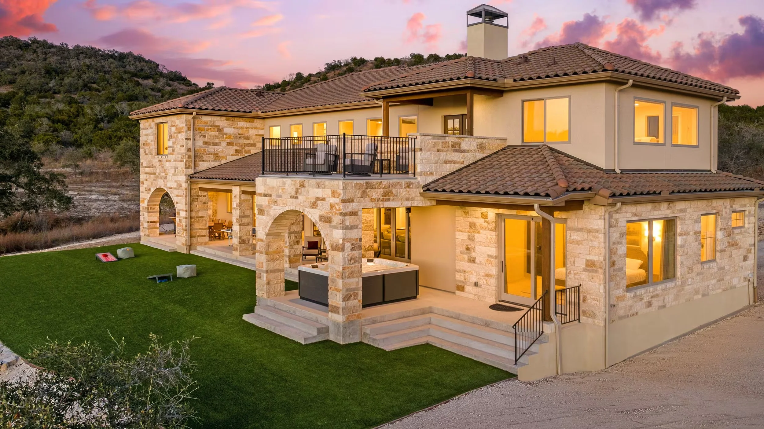 Side view of a modern house with stone walls, green lawn, and clear blue sky with clouds.