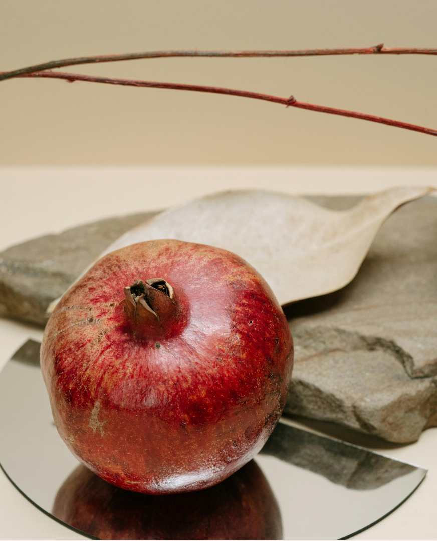 Pomegranate on a reflective surface, symbolizing growth, clarity, and thoughtful financial decision-making.