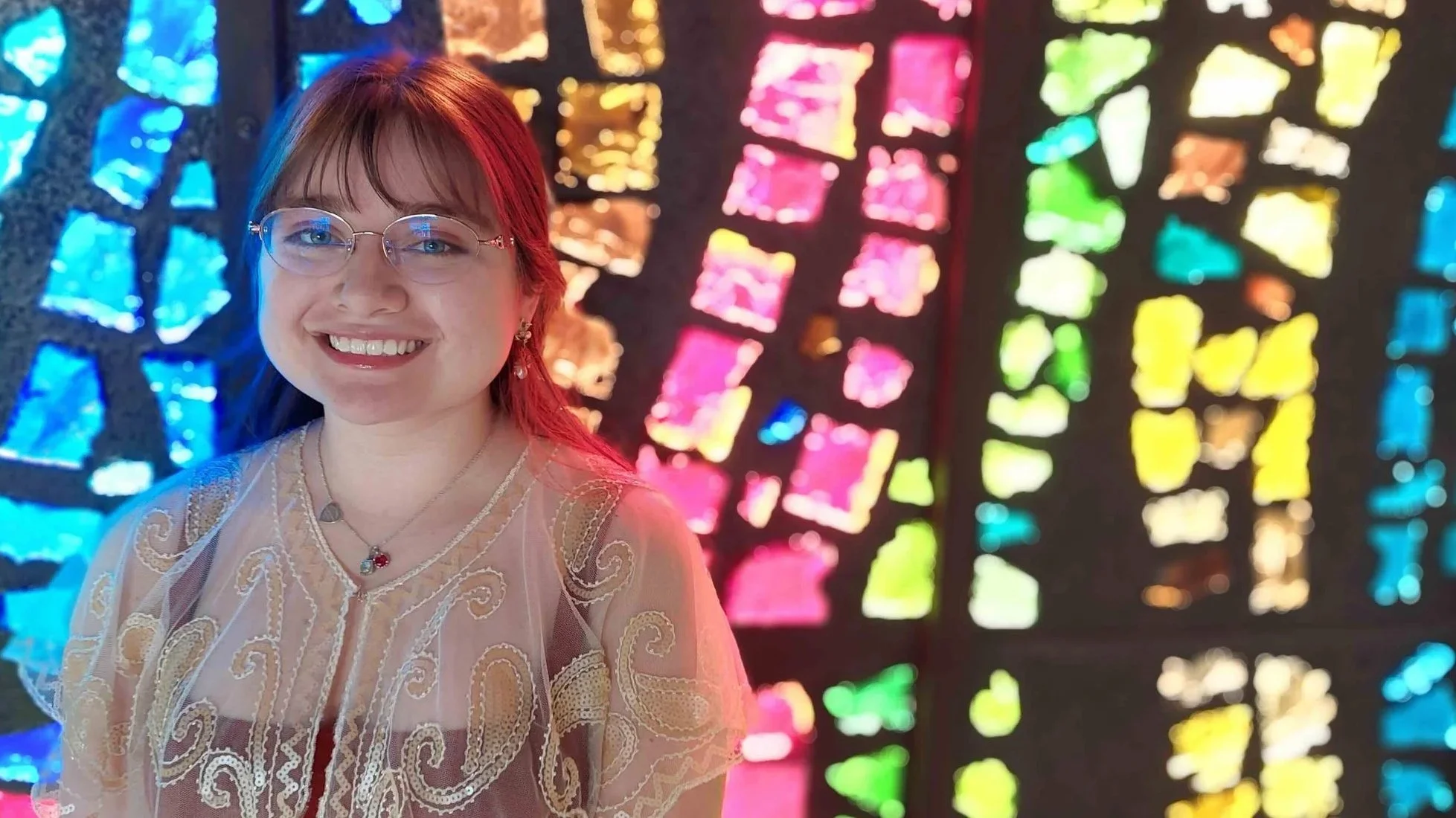 student portrait with brightly colored stained glass behind
