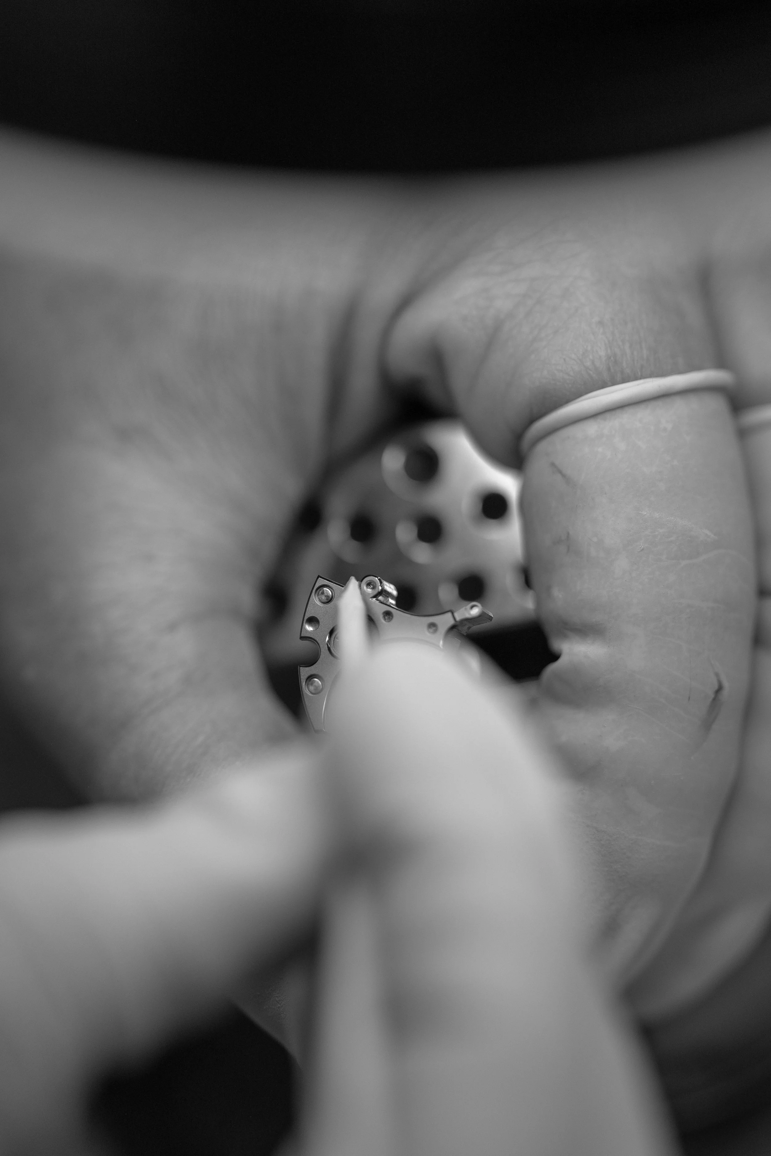 Close-up black-and-white photo of an artisan polishing the N01 calibre bevels.
