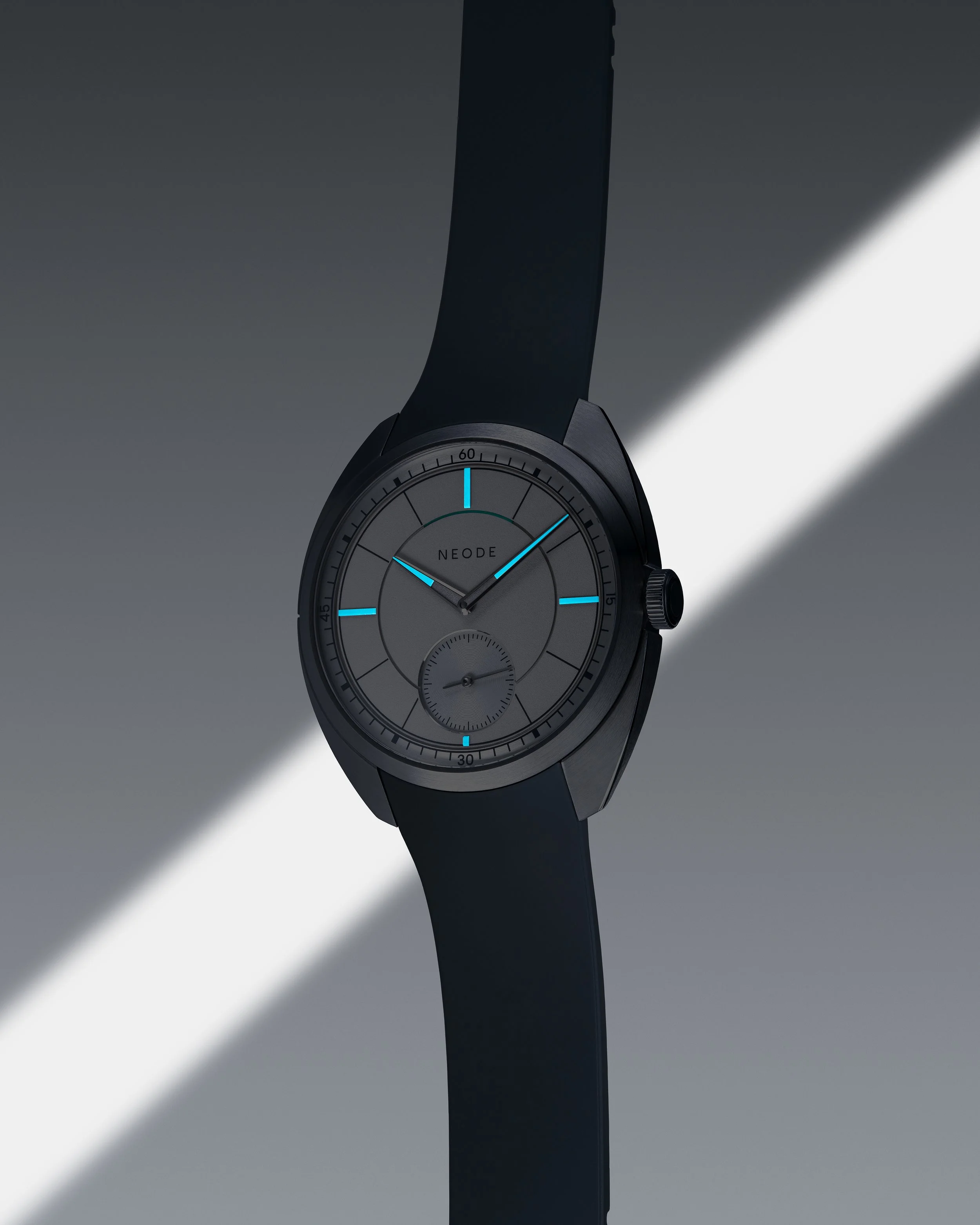 Close-up of a modern wristwatch with a black strap and a grey dial, displaying luminous markers and hands, with the brand name 'NEODE' on the face, set against a dark gradient background with diagonal light streaks.