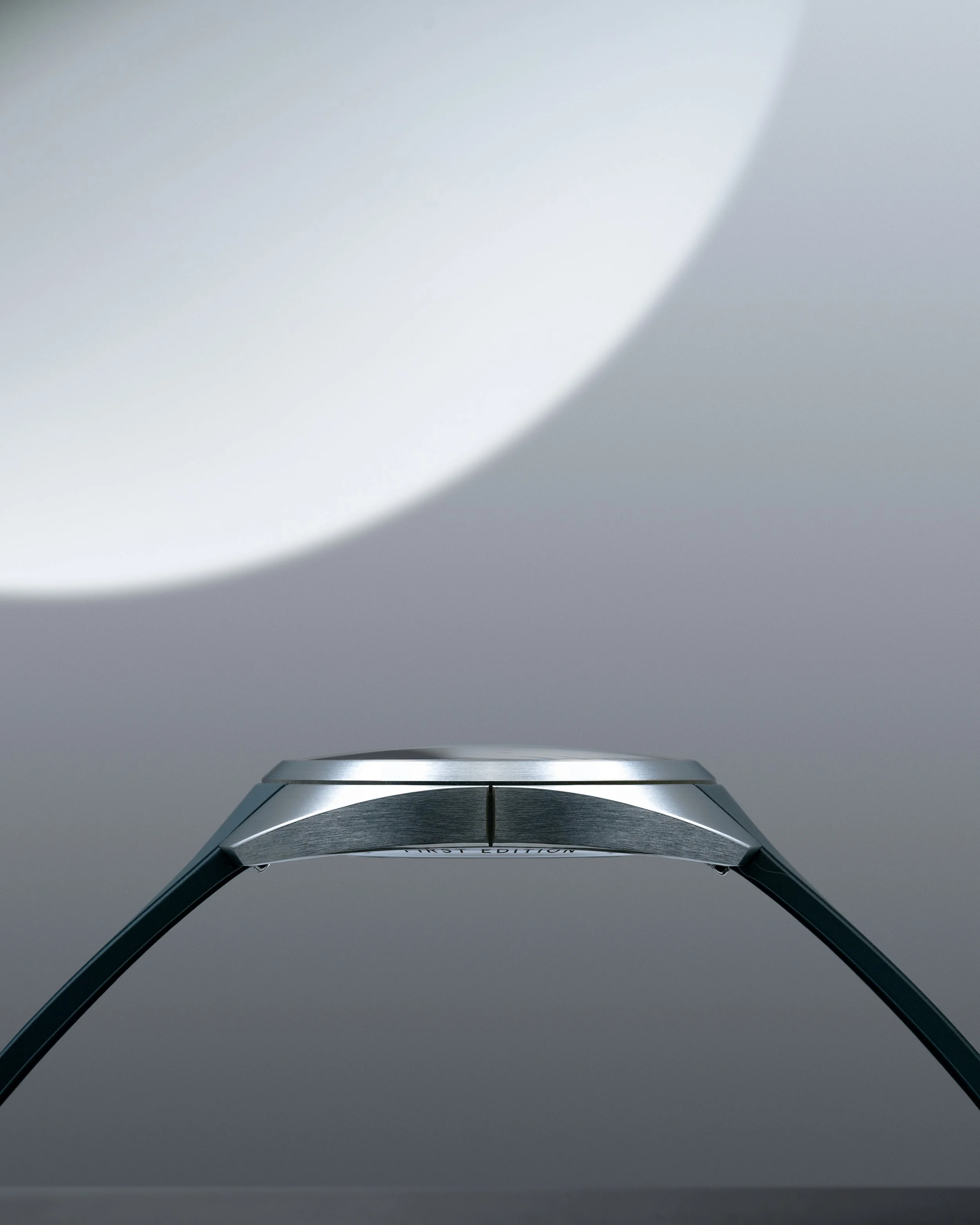 Close-up of the N01 timepiece's sleek metallic profile on a grey background and with a dark grey strap