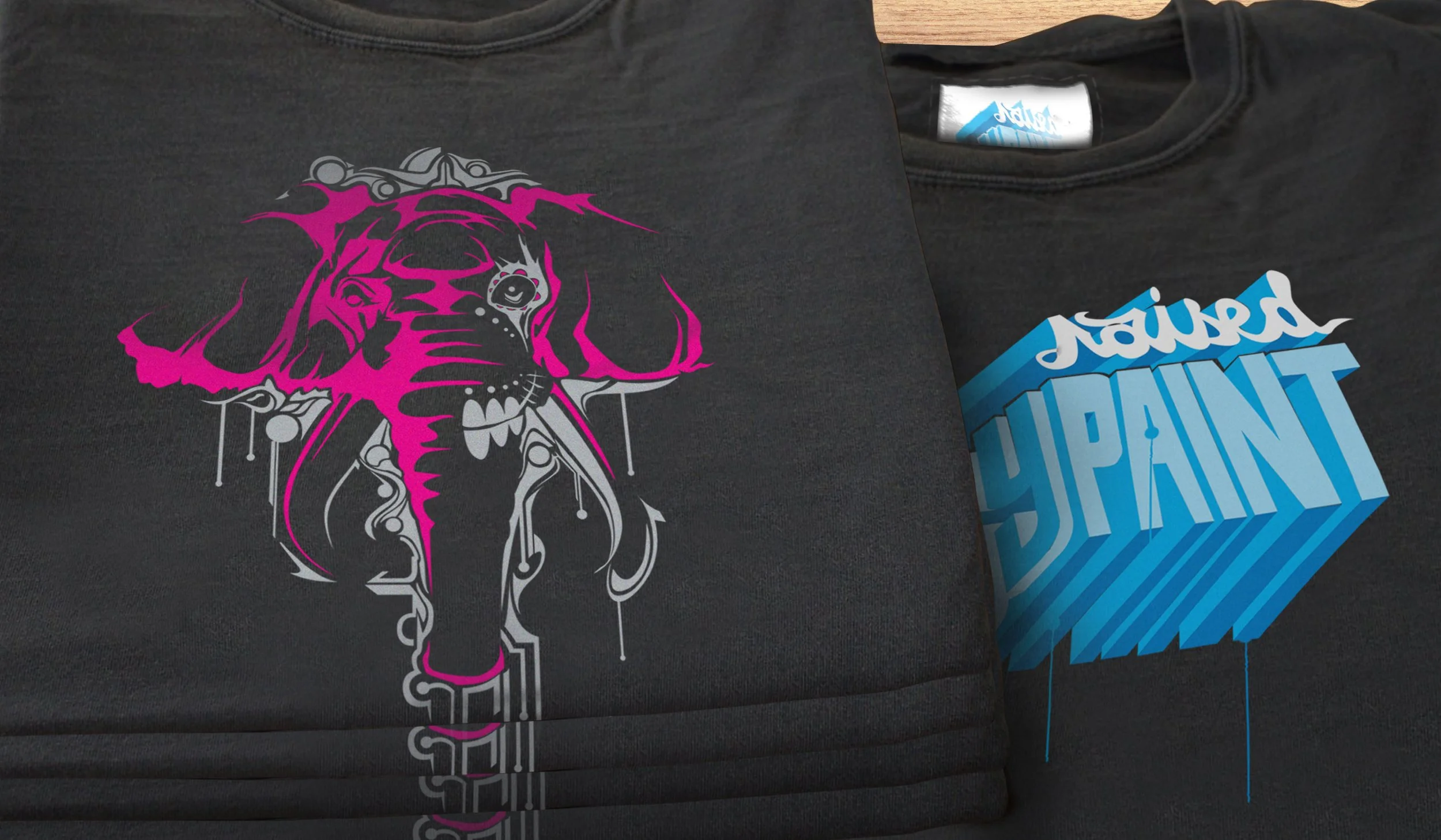 Raised By Paint close up of shirts with screen printed elephant and raised by paint logo.