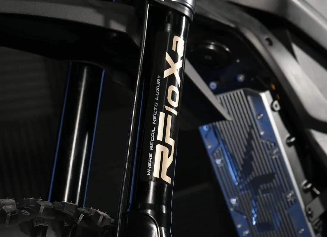 Close-up of an electric motorcycle frame showing the motor, suspension, and battery.