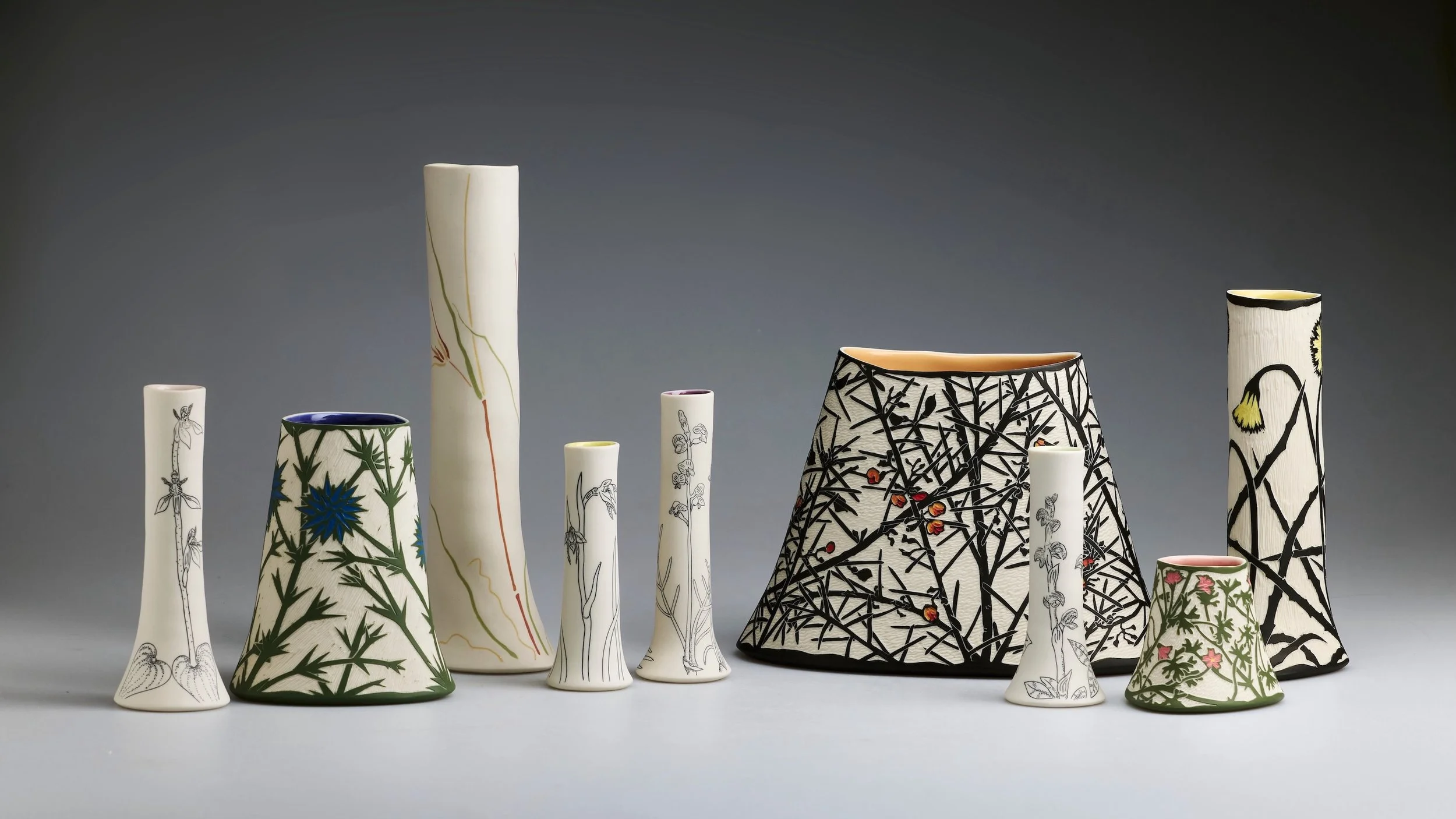 Set of eleven decorative vases with various plant and floral patterns, displayed against a neutral background.