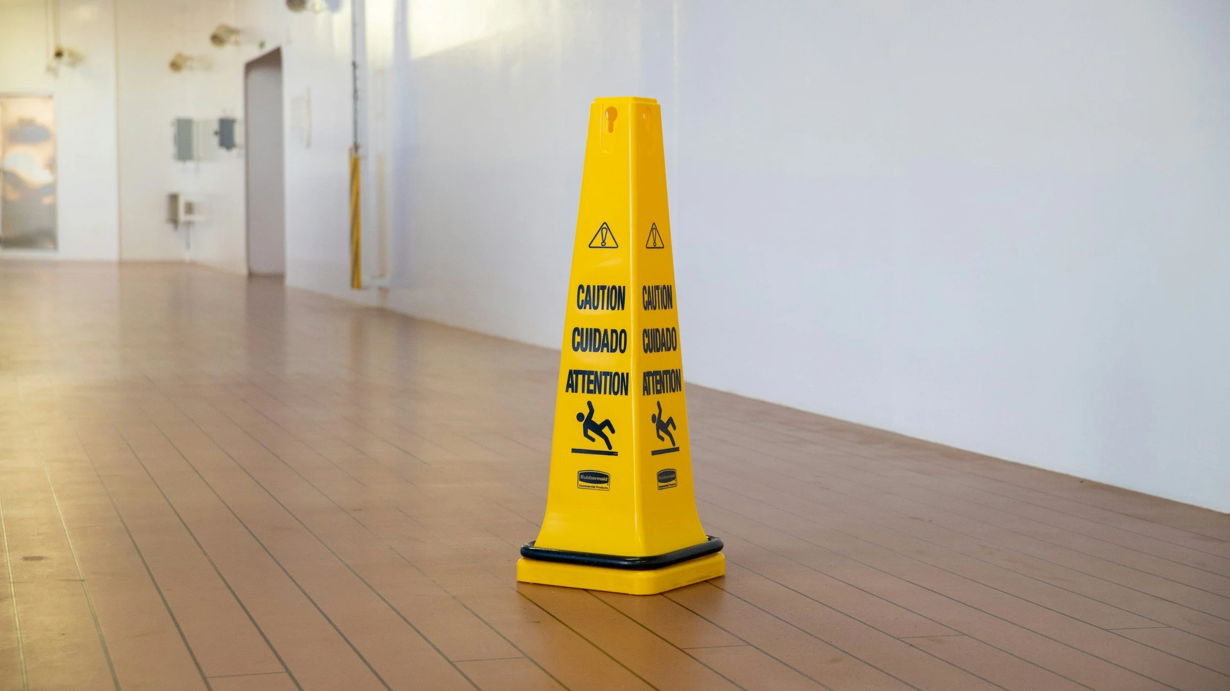 Tiled hallway with yellow caution cone warning of a possible slippery floor