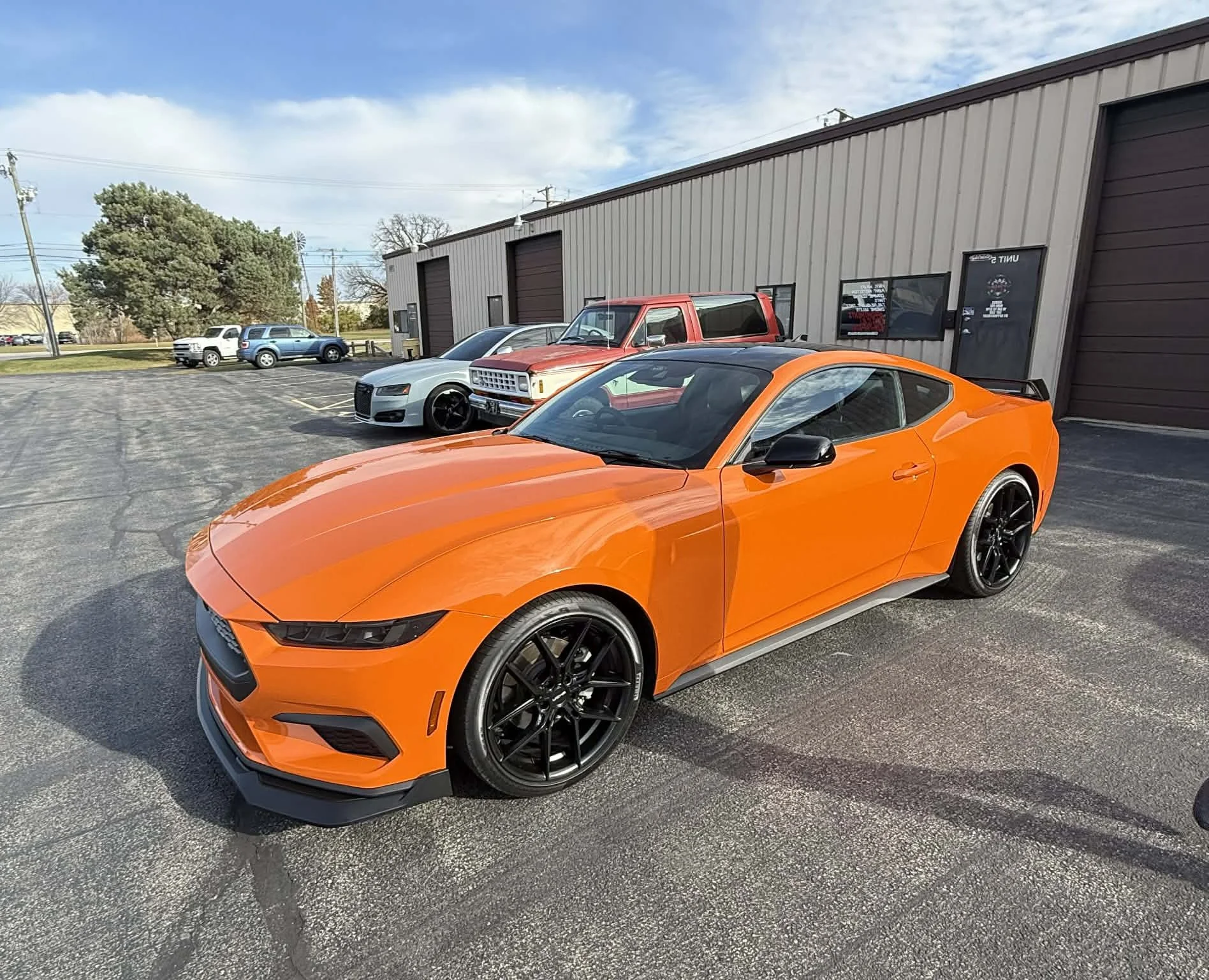 Ford Mustang wrapped in 3M high-gloss orange vinyl, showcasing the full vehicle color change and brilliant glossy finish.