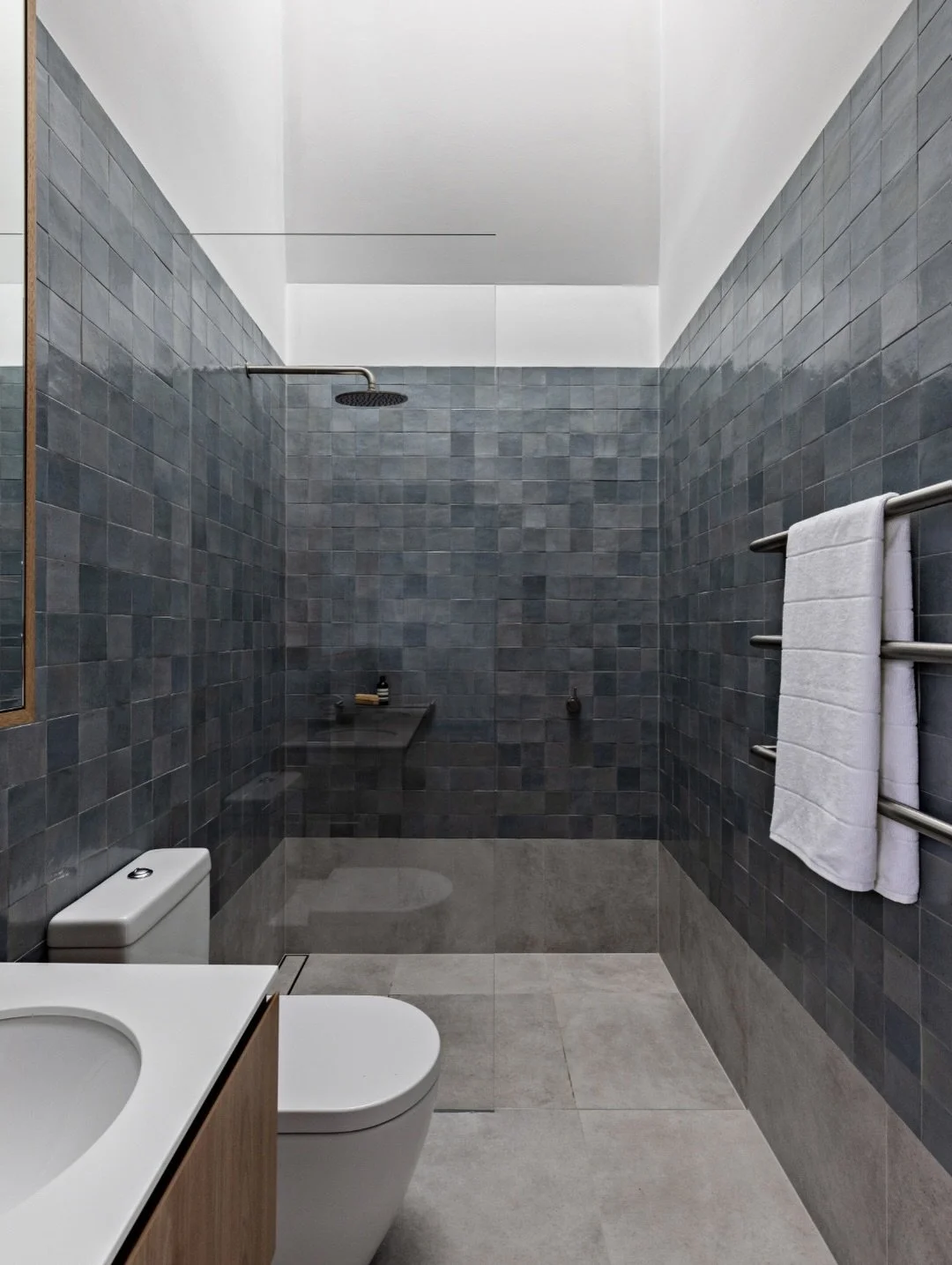 This Bondi bathroom showcases how custom clear glass shower screens complement bold tile choices without competing for attention. The muted steel blue creates a calming backdrop while our frameless installation keeps the focus on the beautiful tilewo