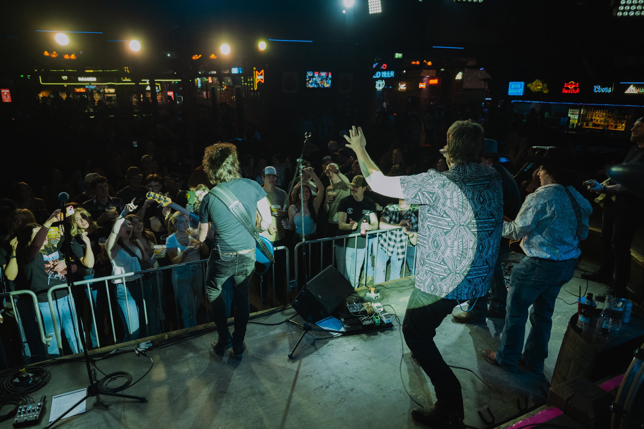 A band performs on stage at a concert venue with a large audience watching.