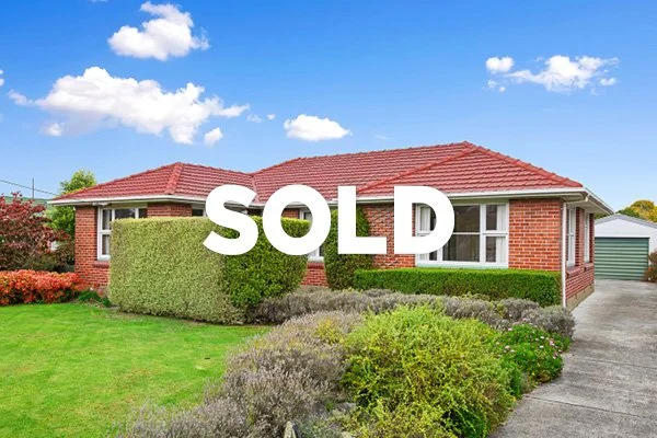 Red brick house with a red tile roof and well-maintained front lawn, with a large 'SOLD' sign overlay.
