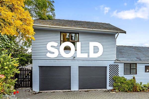 A house with a large white 'SOLD' sign over the garage doors.