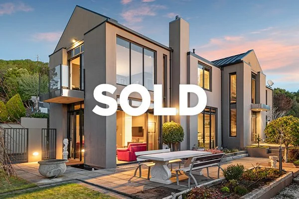 Modern two-story house with large windows and a landscaped backyard, with the word 'SOLD' overlayed.