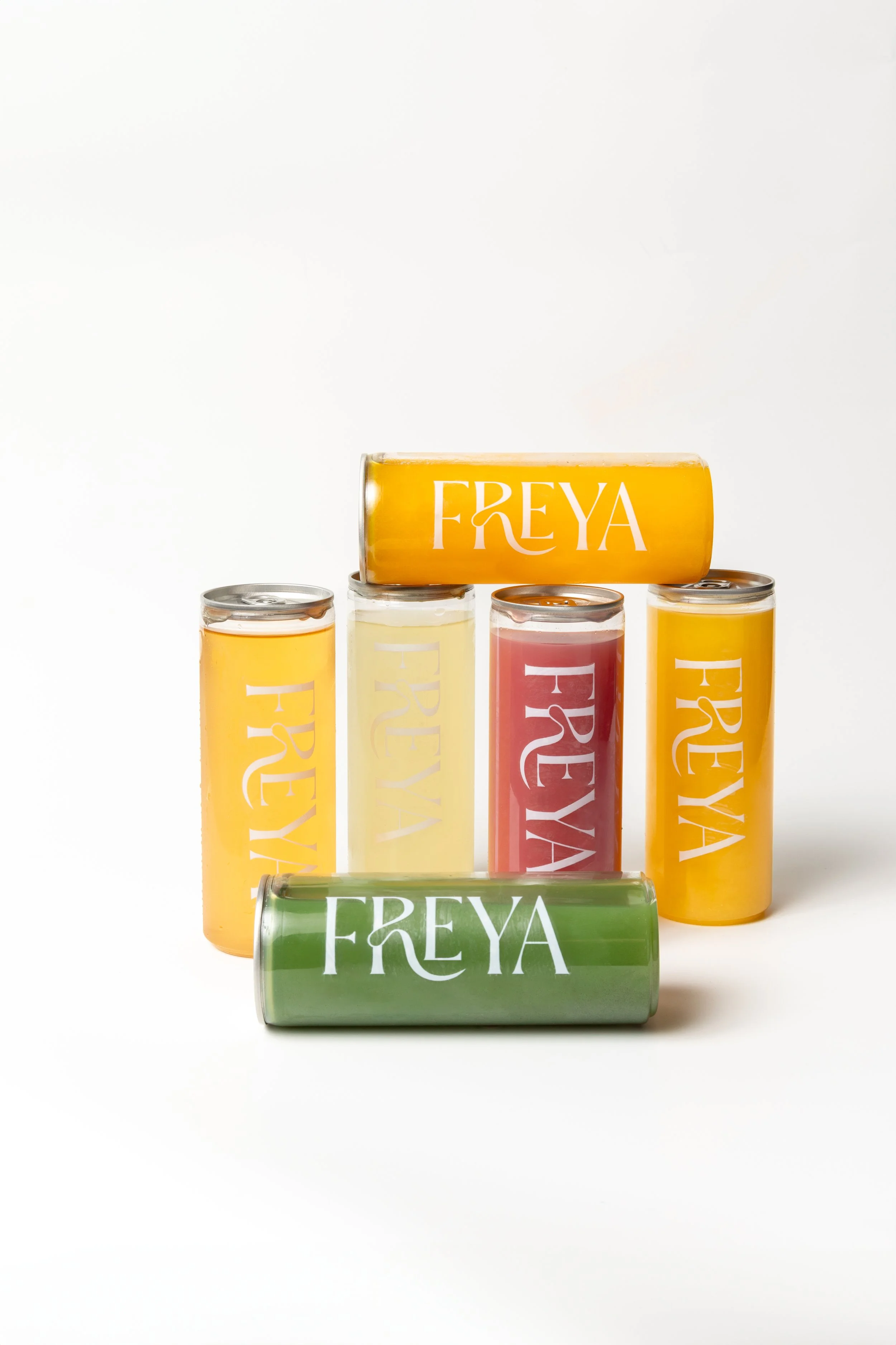 Six cans of Freya beverages in yellow, pink, and green colors arranged in a pyramid shape with a white background.