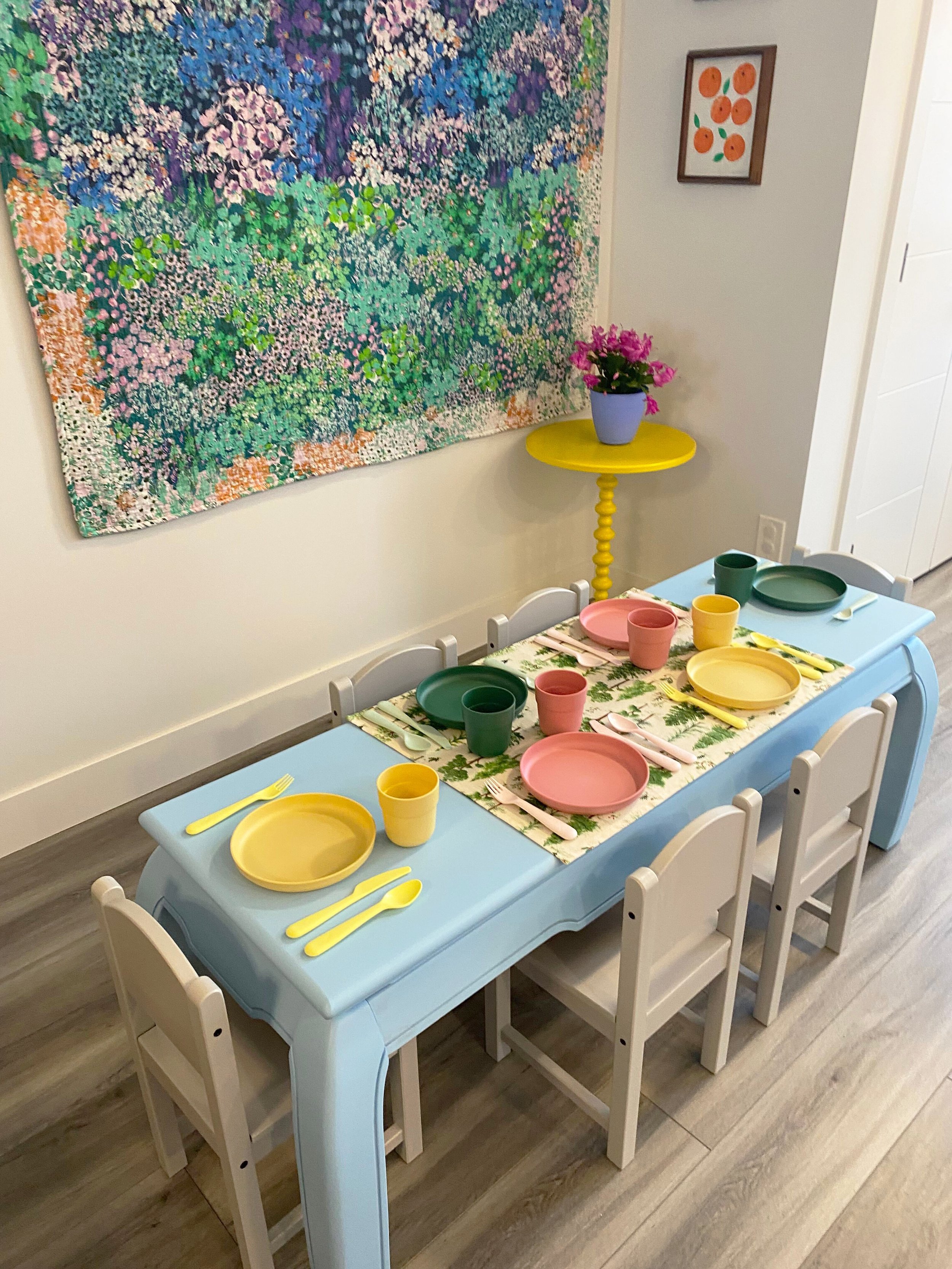 A light blue kids dining table with chairs and place settings.