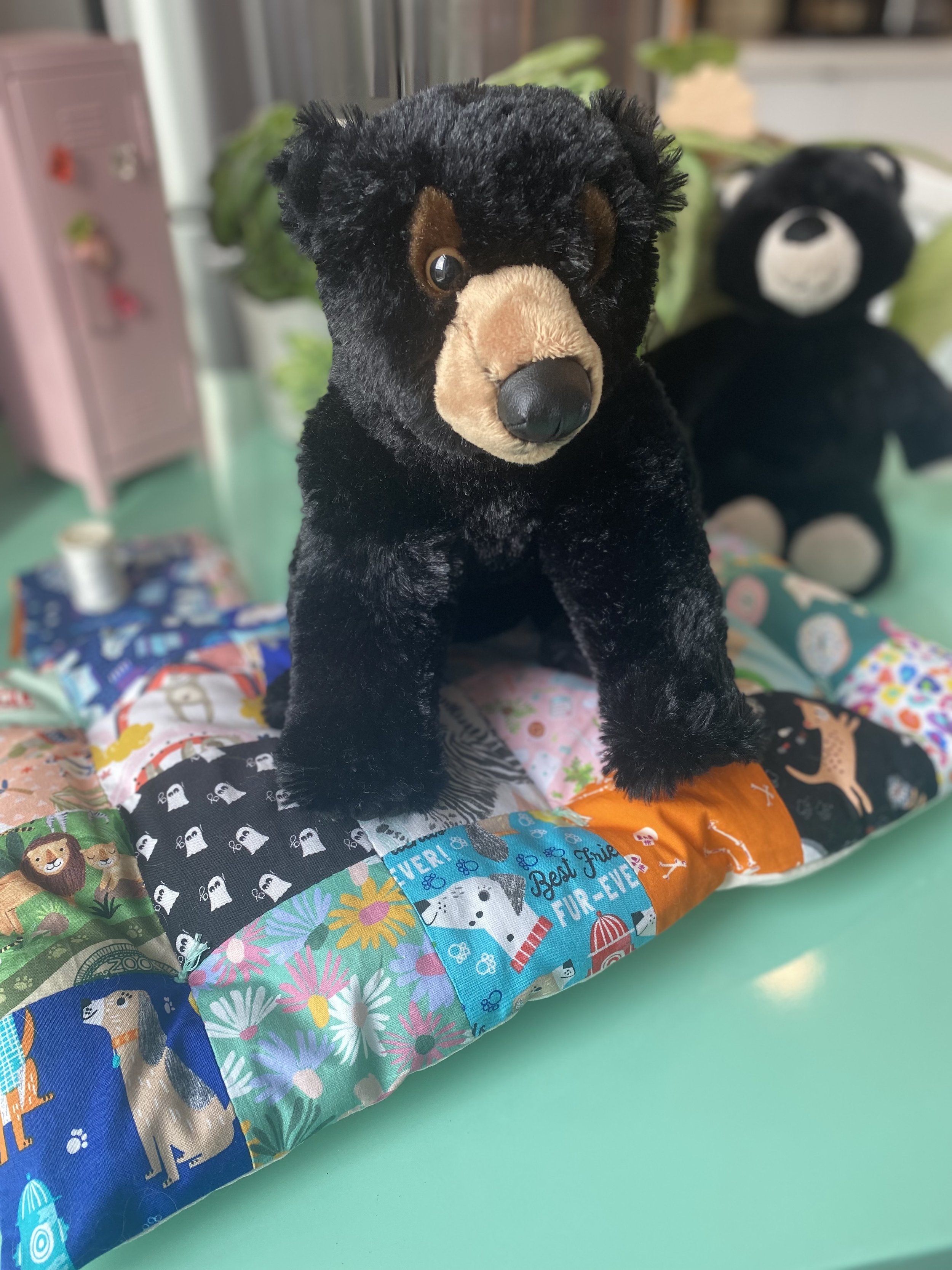 A teddy bear sitting on a patchwork mattress.