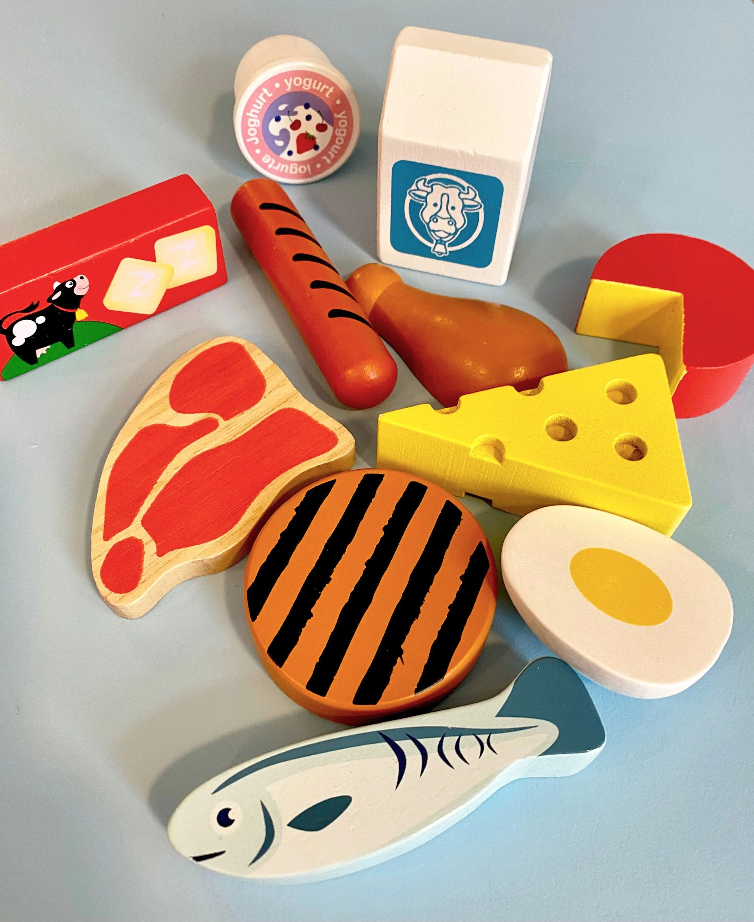 Wooden toy food such as butter, fish, cheese, and steak.