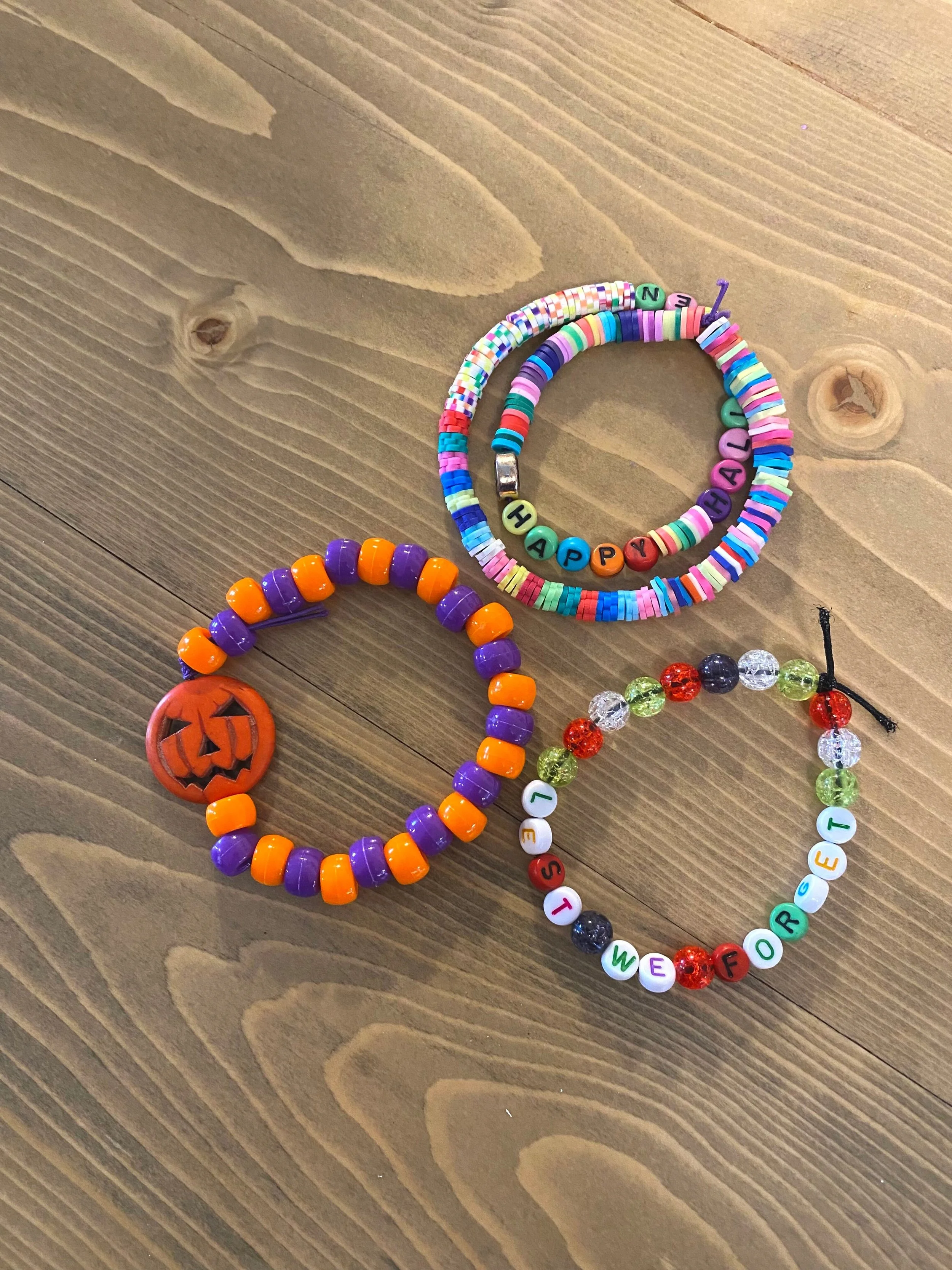 Three hand-made bracelets on a wood table.