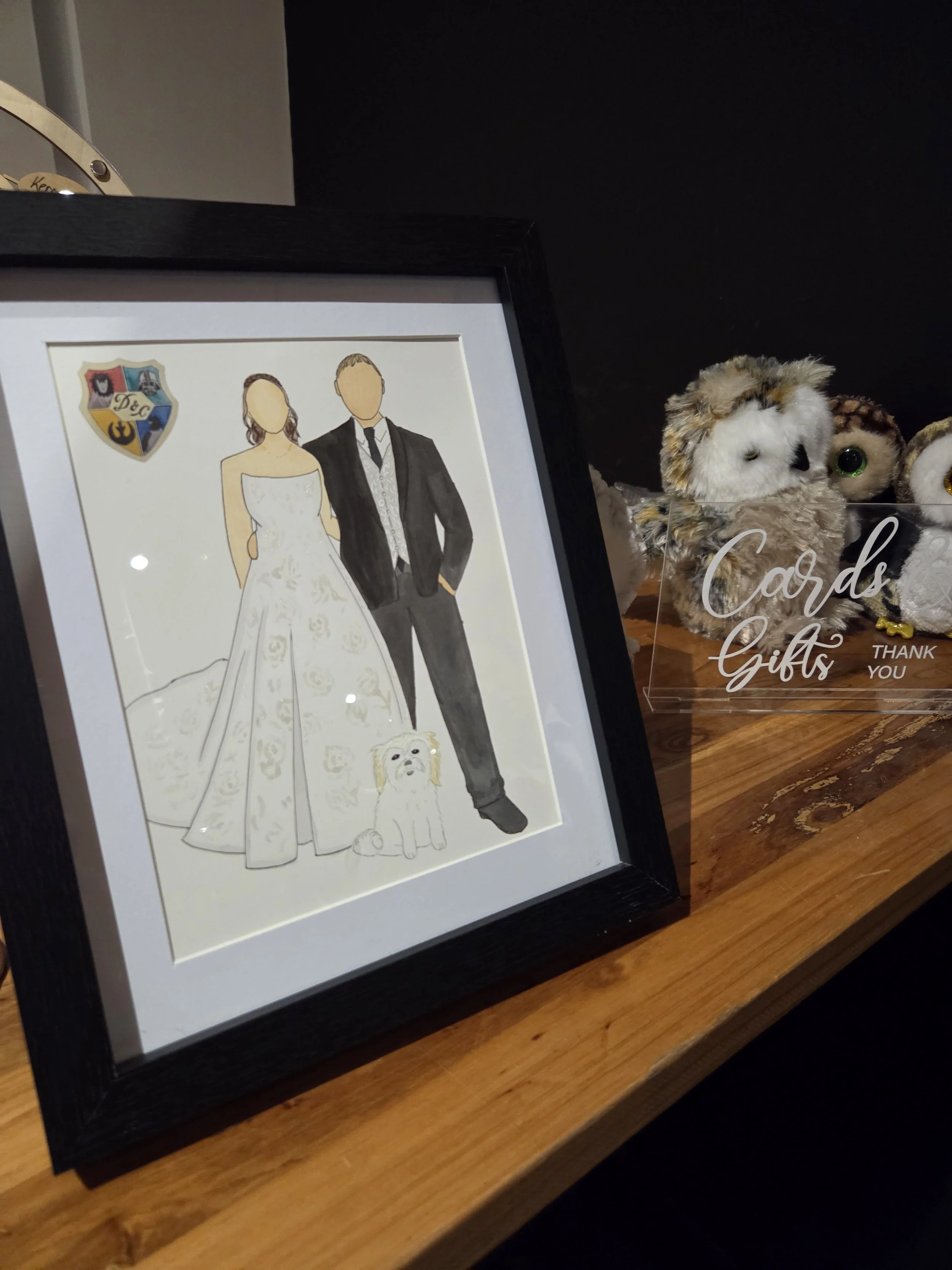 Illustration of a bride and groom with arms around each other, with their dog sitting in front. The bride is wearing a strapless white wedding dress and the groom is in a black tuxedo with a tie.