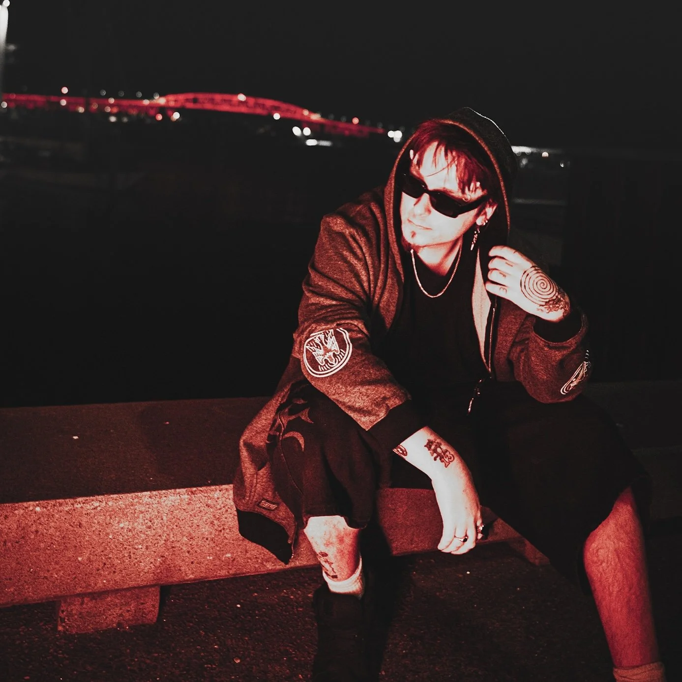 Red tinted photo of day13n sitting in front of the Auckland Harbour Bridge