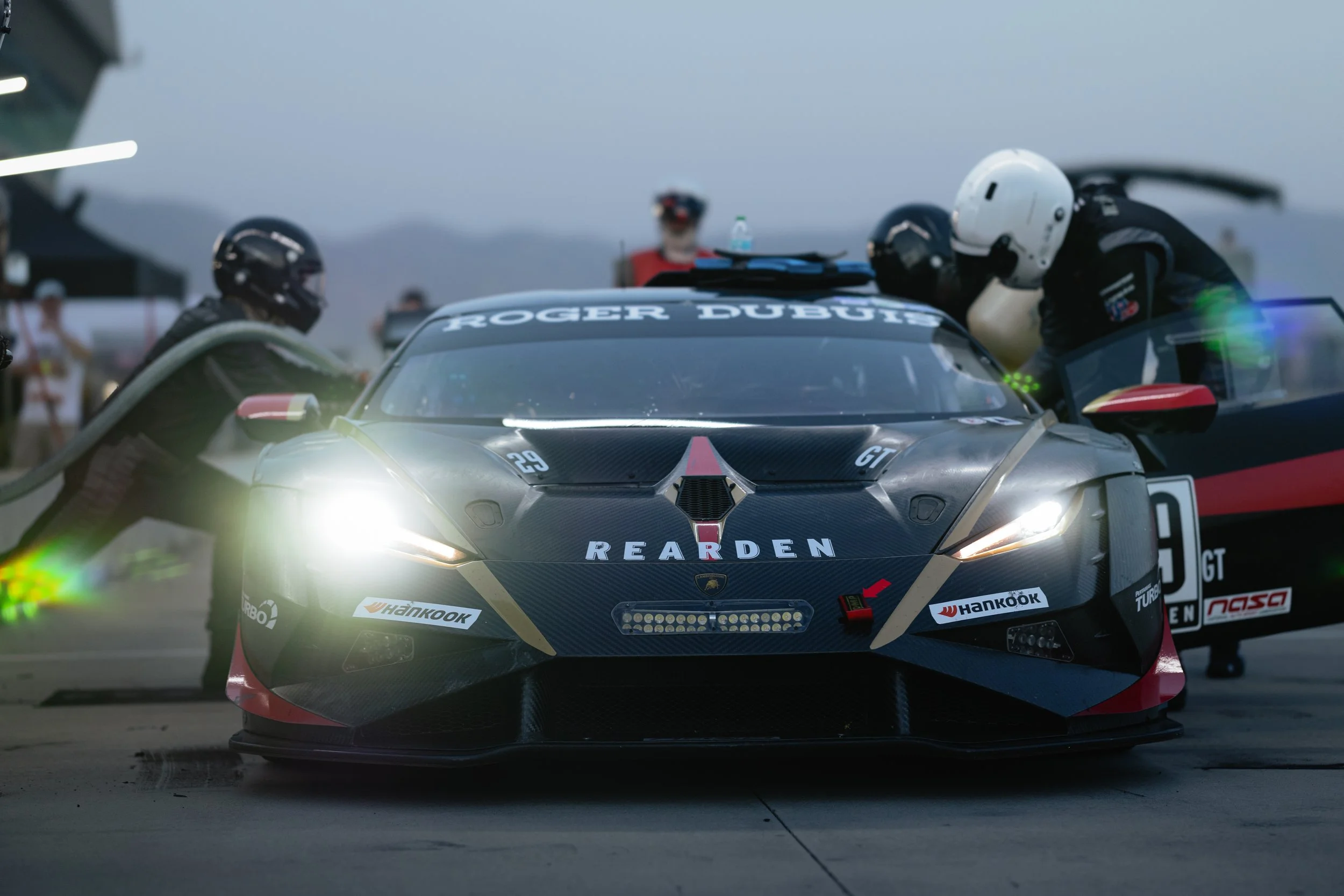 Image shows the pit crew working on a race prepped Lamborghini during a pit stop of an endurance race. This includes refueling, and driver change.