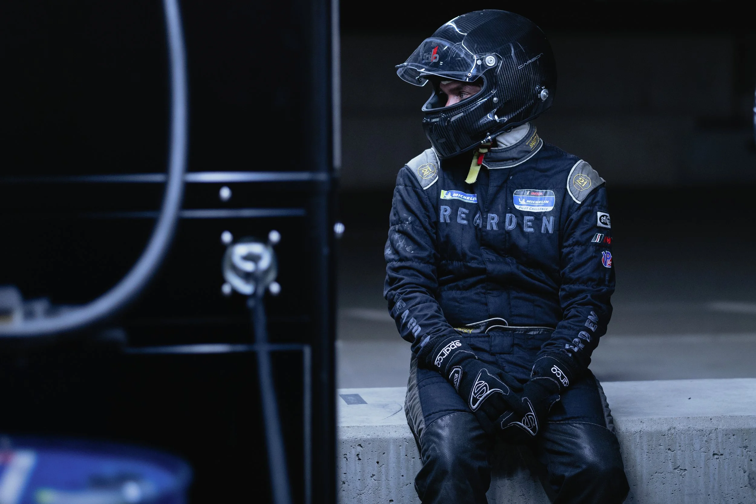 A race crew member sits down after a successful pit stop to catch his breath.