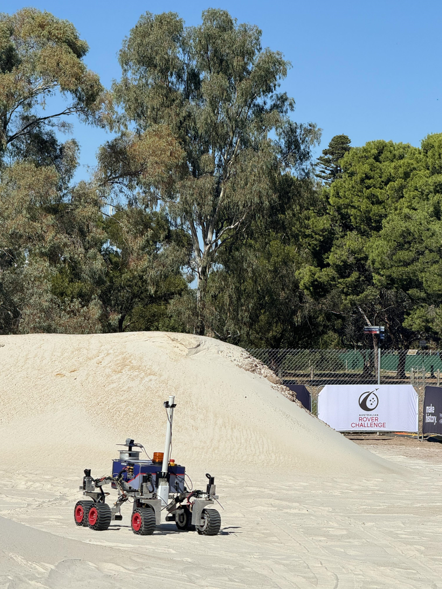 a rover on sand with trees behind it
