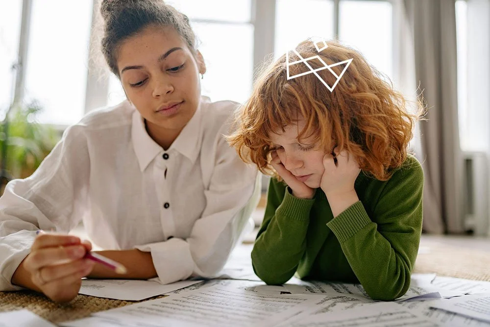 Two young girls studying or doing homework together on the floor in a well-lit room.