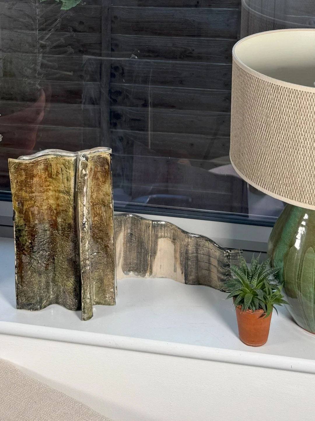 Rooftile fragment 2 by ceramic Artist Cristina Lorenzet displayed on windowsill with other Rooftile sculpture.