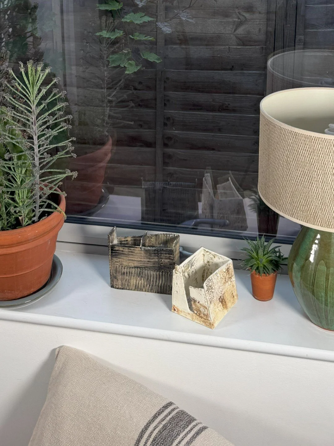 Patina on a building by ceramic Artist Cristina Lorenzet, white stoneware sculpture, with other artwork on windowsill.