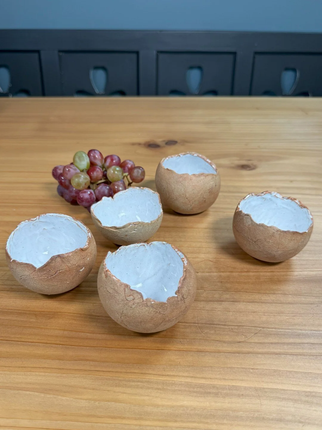 Group of small handmade crackle bowls by ceramic Artist Nupur Narain DeTar, displayed a group of bowls with a bunch of grapes.