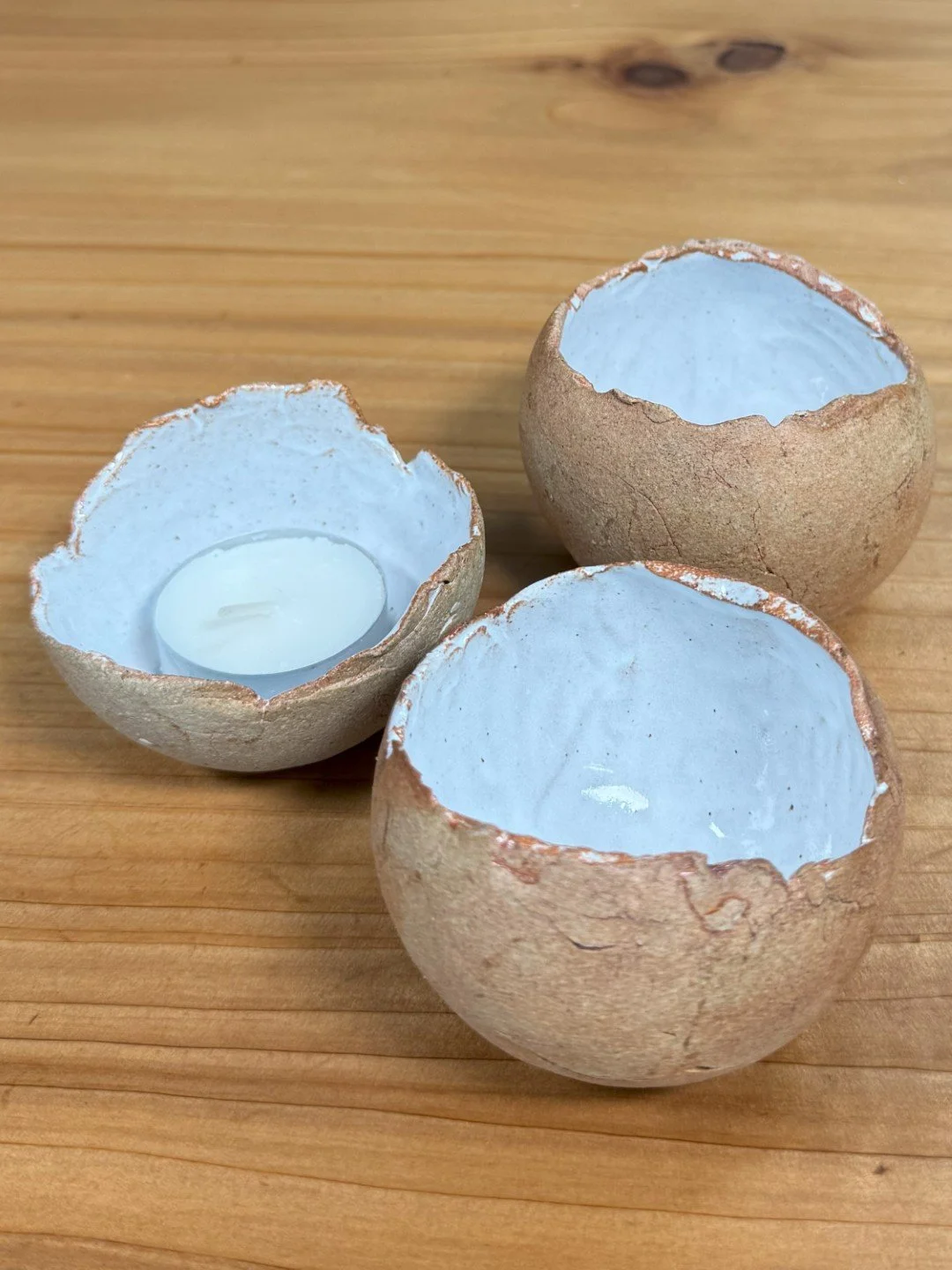 Group of small handmade crackle bowl by ceramic Artist Nupur Narain DeTar, displayed with a tealight inside one of them.